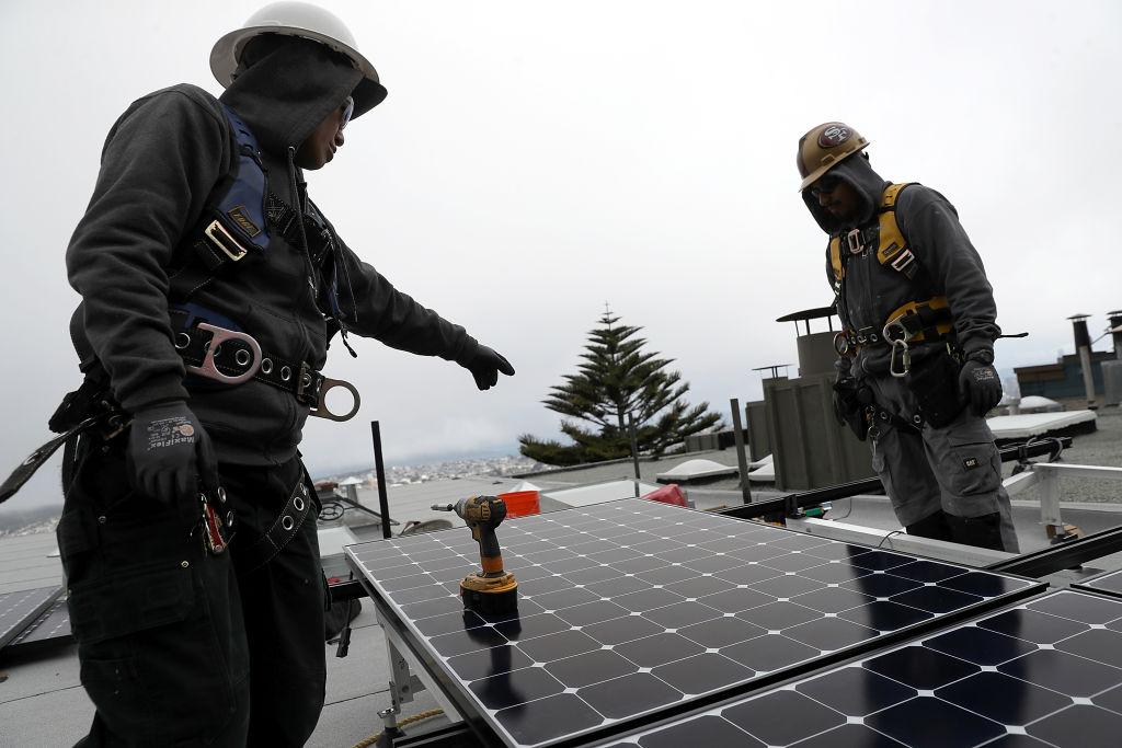 Luminalt solar installers Pam Quan (L) and Walter Morales (R) install solar panels on the roof of a home on May 9, 2018 in San Francisco, California. CREDIT: Justin Sullivan/Getty Images