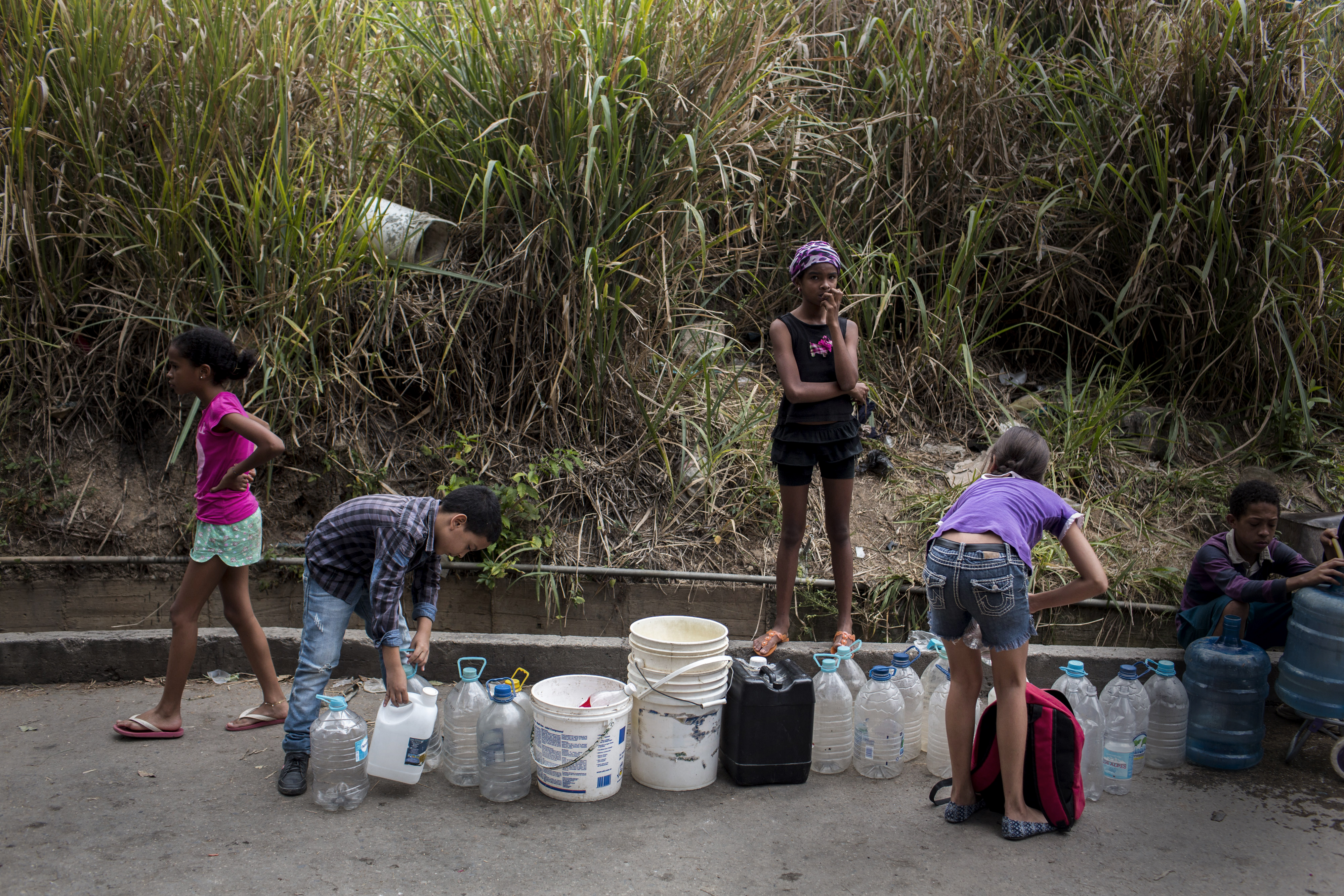Children standing in line and waiting for their jugs and buckets to be filled with drinking water in Caracas, Venezuela. (PHOTO CREDIT: Manu Quintero/picture alliance /Getty Images)