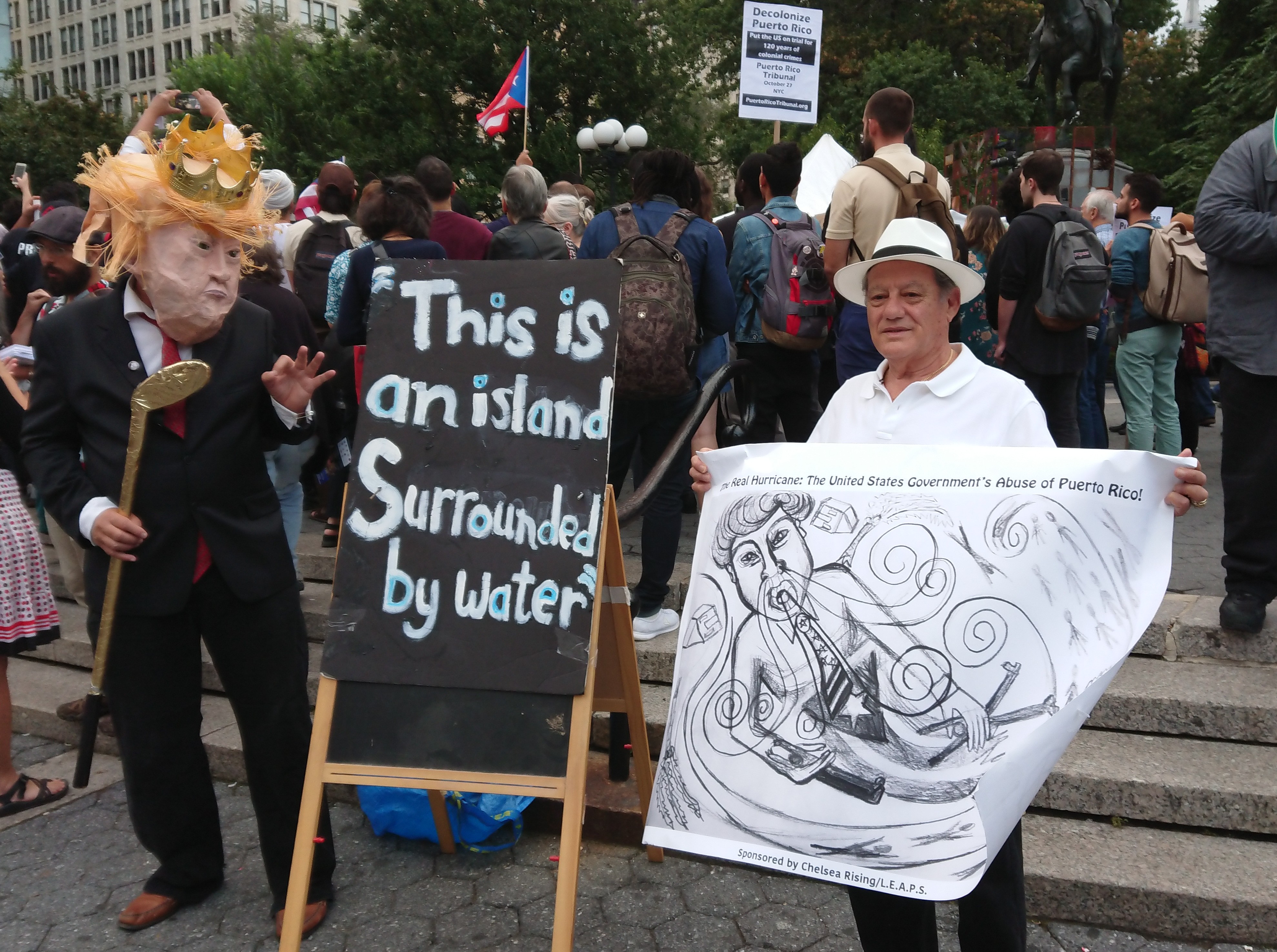 In defending FEMA's slow responses to Hurricane Maria, President Trump pointed out that Puerto Rico is "This is an island surrounded by water, big water, a protester points out Manhattan is also an island. CREDIT: D. Parvaz/ThinkProgress.
