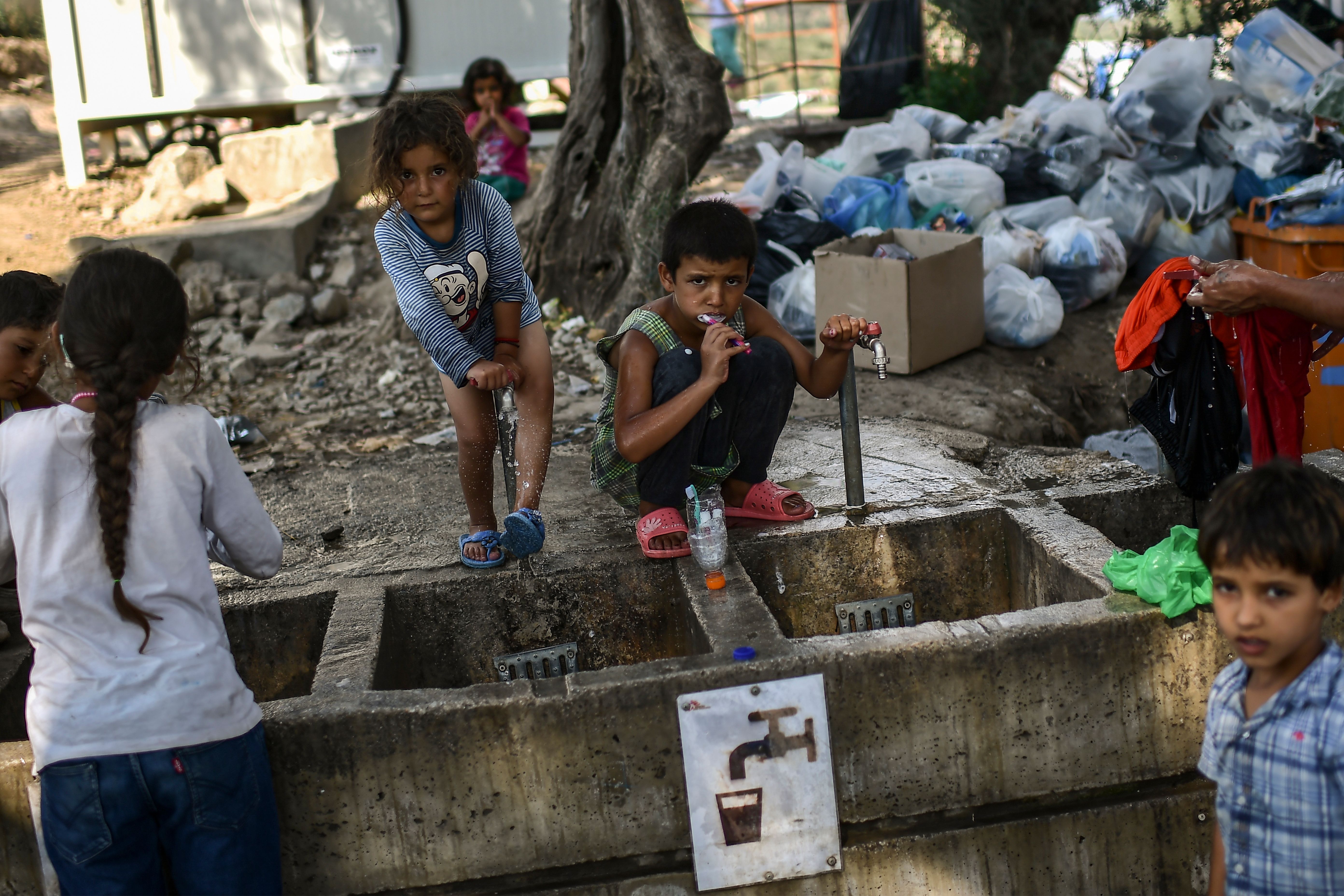 Refugees and migrants clean themselves and wash their clothes at a camp outside the Moria refugee camp in the island of Lesbos on August 5, 2018. CREDIT: Aris Messinis/AFP/Getty Images.