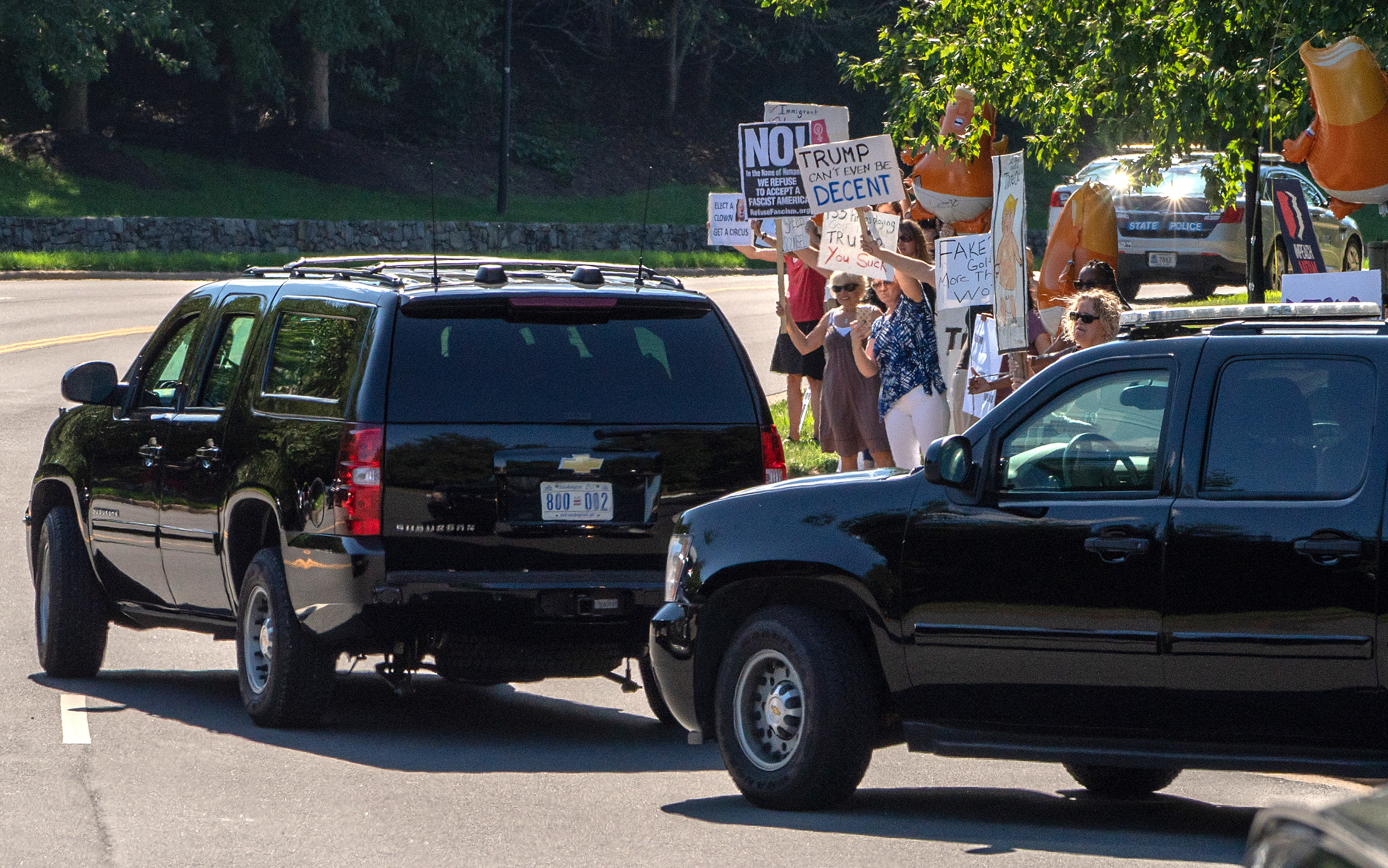 STERLING, VA - SEPTEMBER 2: (AFP OUT) Protestors stand at the curb with signs against President Donald Trump as his motorcade departs the Trump National Golf Club on September 2, 2018 in Sterling, Virginia. (Photo by Ken Cedeno-Pool/Getty Images)