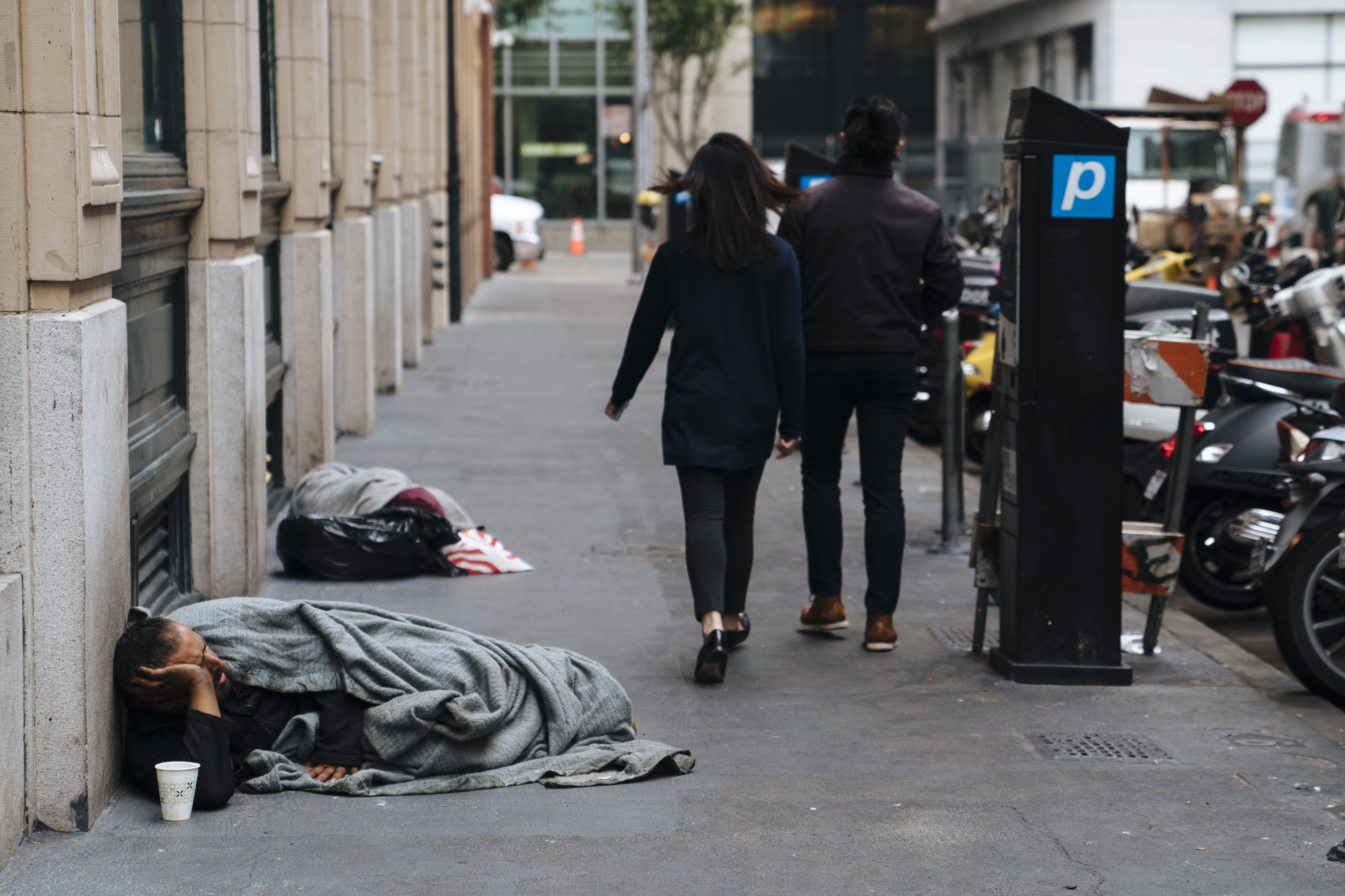 SAN FRANCISCO, CA - AUGUST 23: People walk by homeless people sleeping n San Francisco, California, on August 23, 2018. (Photo by Mason Trinca for The Washington Post via Getty Images)