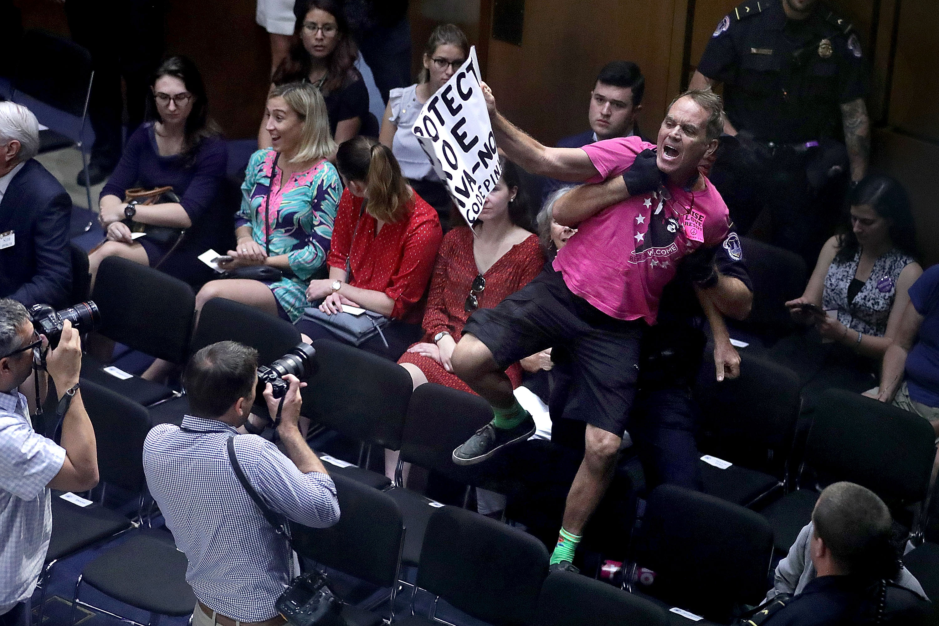 Code Pink demonstrator Tighe Barry is pulled down from a chair by a U.S. Capitol Police officer after he interrupted the third day of Supreme Court nominee Judge Brett Kavanaugh's confirmation hearing in the Hart Senate Office Building on Capitol Hill September 6, 2018 in Washington, DC. (Credit: Chip Somodevilla/Getty Images)