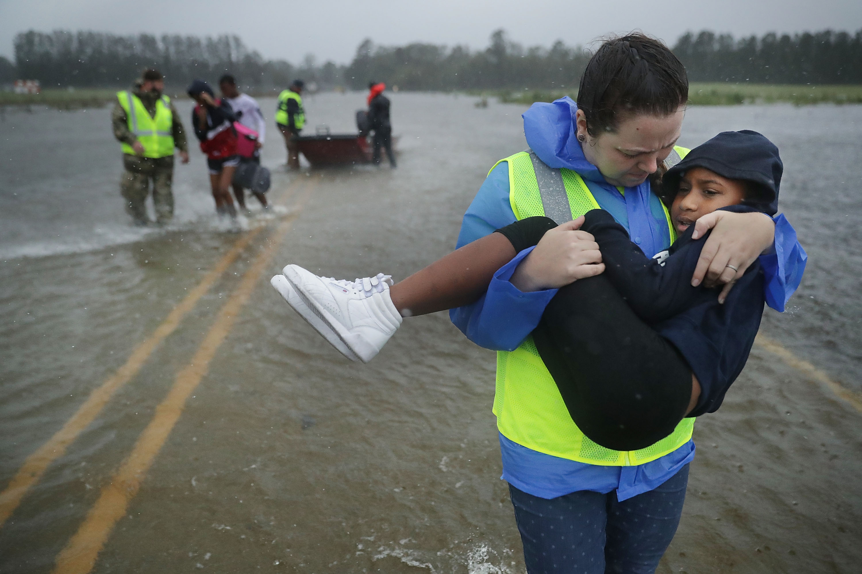 Volunteer Amber Hersel from the Civilian Crisis Response Team helps rescue 7-year-old Keiyana Cromartie and her family from their flooded home September 14, 2018 in James City, United States. CREDIT: Chip Somodevilla/Getty Images