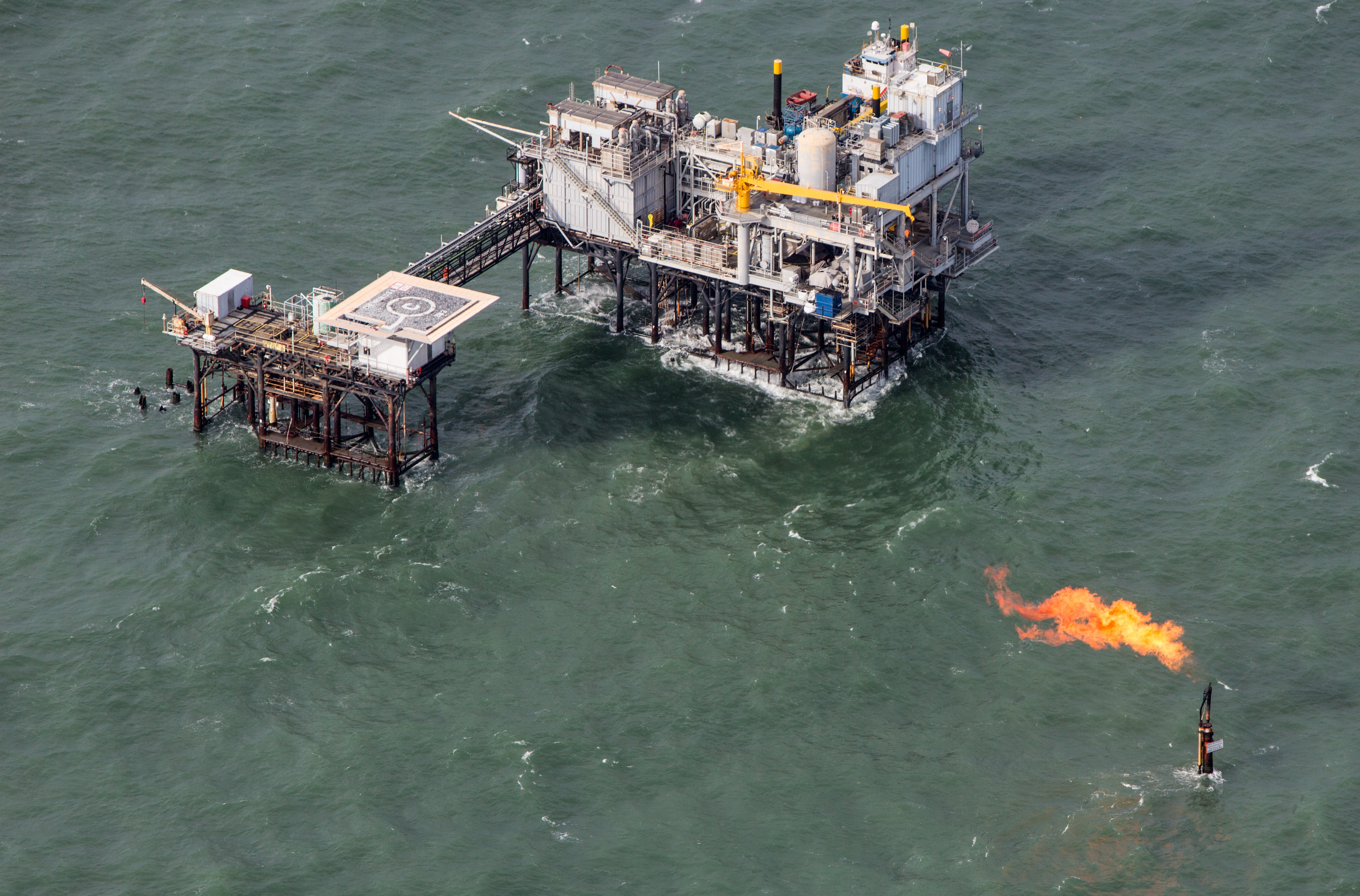 Aerial view of an oil production platform in the Gulf of Mexico with a flare of the coast of Port Fourchon, Louisiana's southernmost port, where land loss due to coastal erosion is estimated to be more than the size of footaball field every hour. CREDIT: Julie Dermansky/Corbis via Getty Images