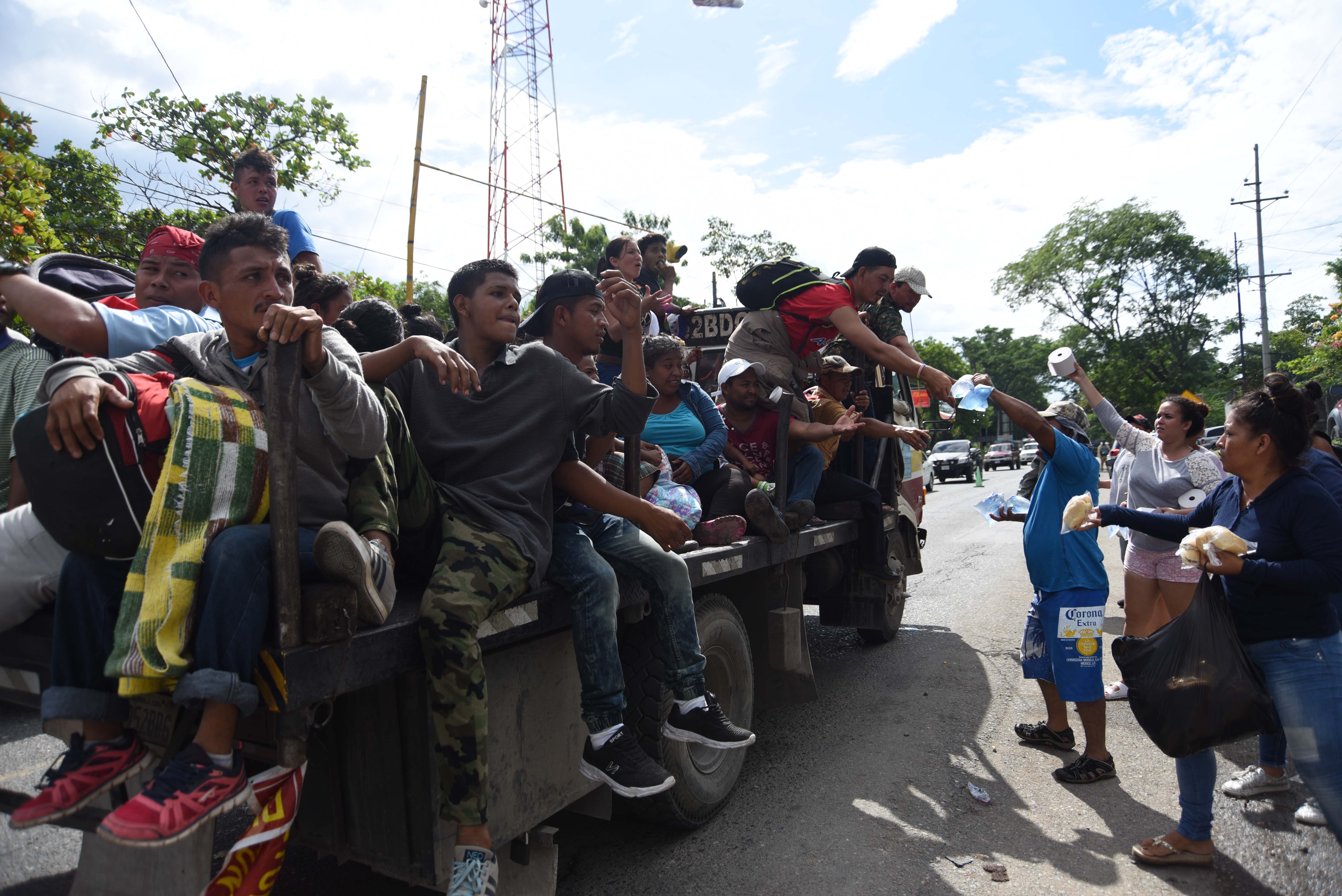 Local residents provide food and drink to Honduran migrants taking part in a caravan to the United States in Teculutan, Guatemala, on October 17, 2018. - Thousands of Honduran migrants marched north on October 17 in a bold attempt to reach the United States, defying threats from President Trump to stop aid to countries that let them pass. (Photo credit: ORLANDO ESTRADA/AFP/Getty Images)