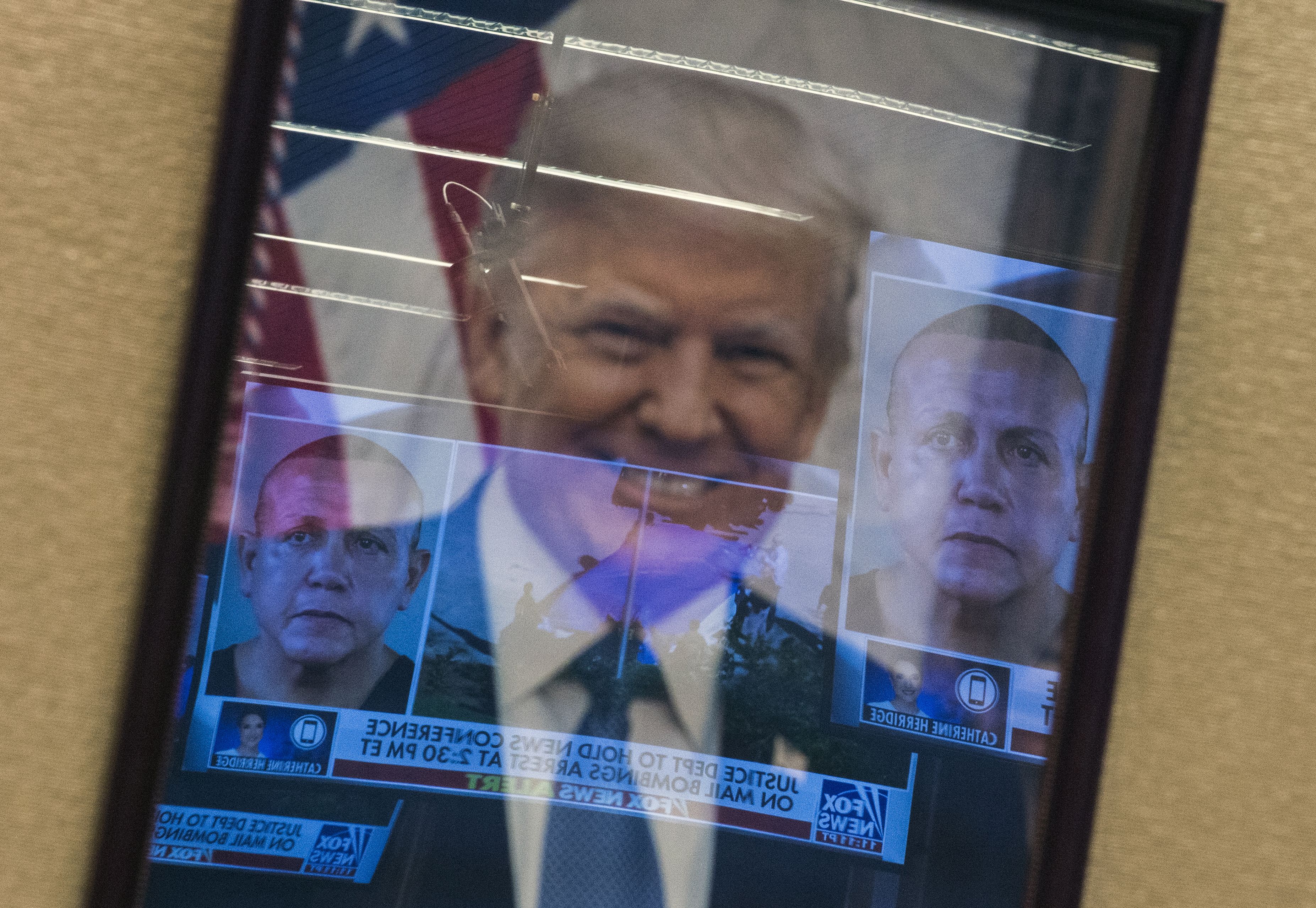 Mugshots of bombing suspect Cesar Sayoc are reflected on a portrait of US President Donald Trump prior to a press conference at the Department of Justice October 26, 2018, following the arrest of Sayoc in Florida. CREDIT: ANDREW CABALLERO-REYNOLDS/AFP/Getty Images