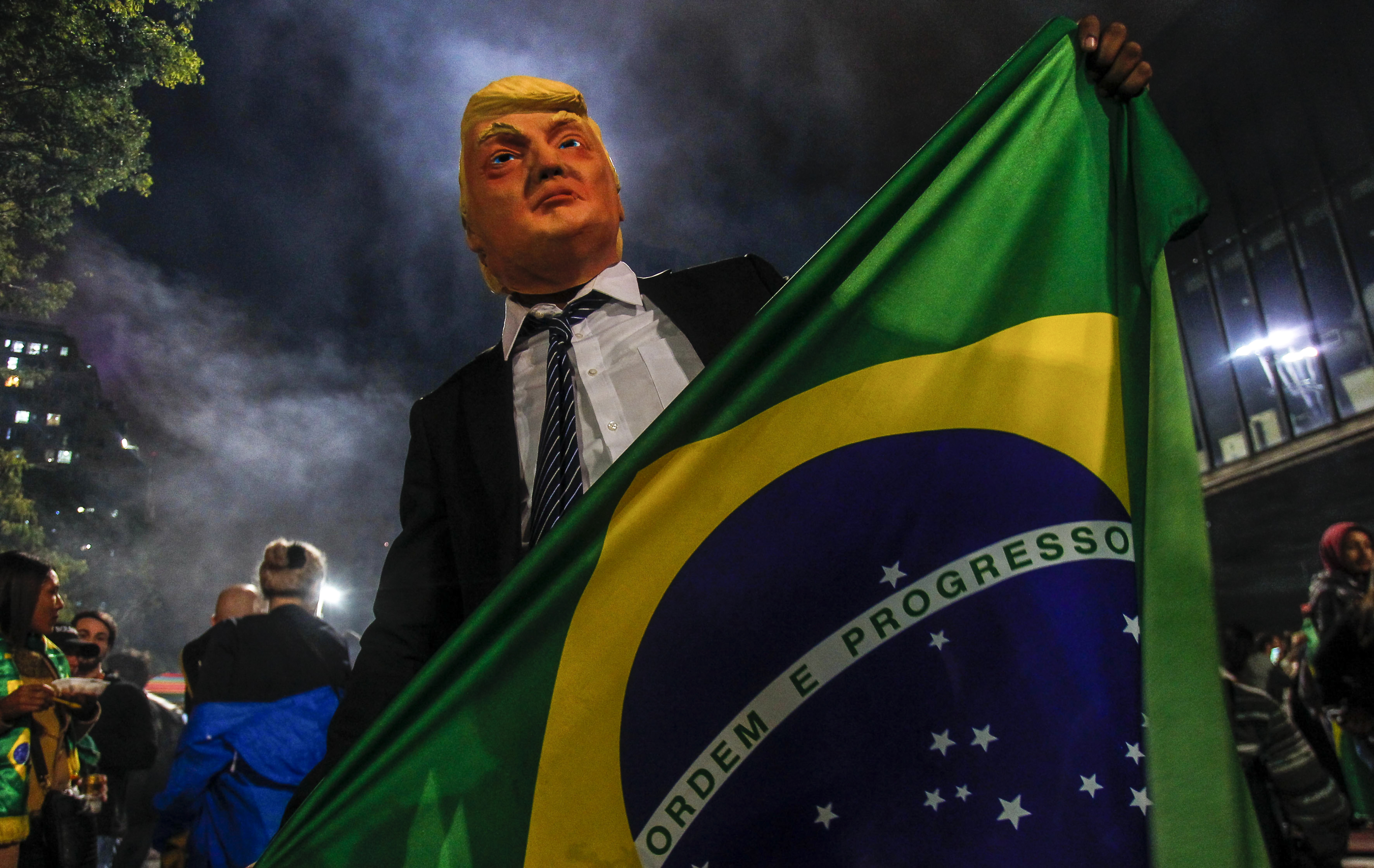A supporter of far-right lawmaker and presidential candidate for the Social Liberal Party (PSL), Jair Bolsonaro, wears a mask of US President Donald Trump as he celebrates after Bolsonaro won Brazil's presidential election, in Sao Paulo, Brazil, on October 28, 2018. CREDIT: Miguel Schincariol/AFP/Getty Images.