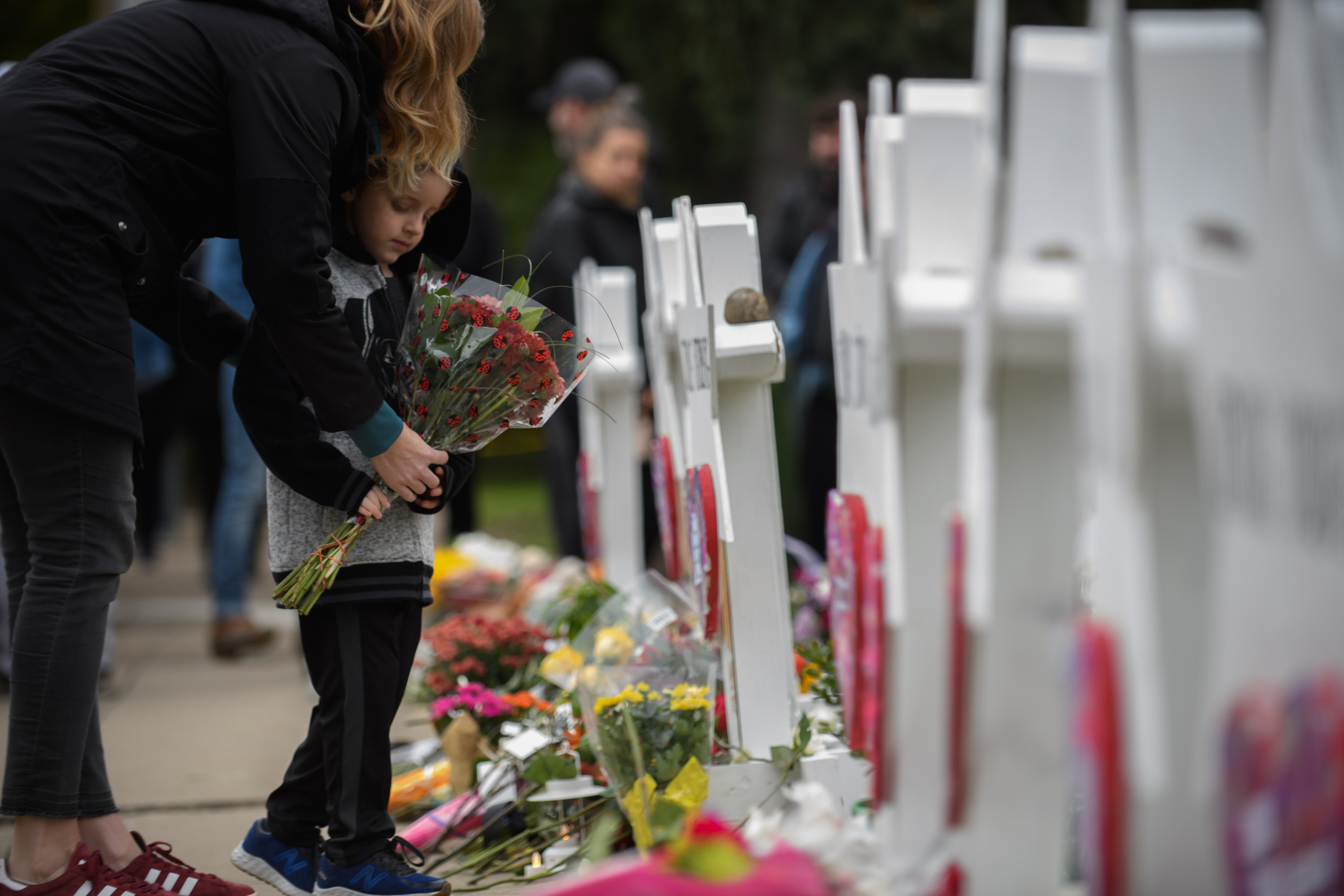 A mother and child place flowers at a memorial for victims of the mass shooting that killed 11 people and wounded 6 at the Tree Of Life Synagogue on October 29, 2018 in Pittsburgh, Pennsylvania. (Credit: Jeff Swensen/Getty Images)