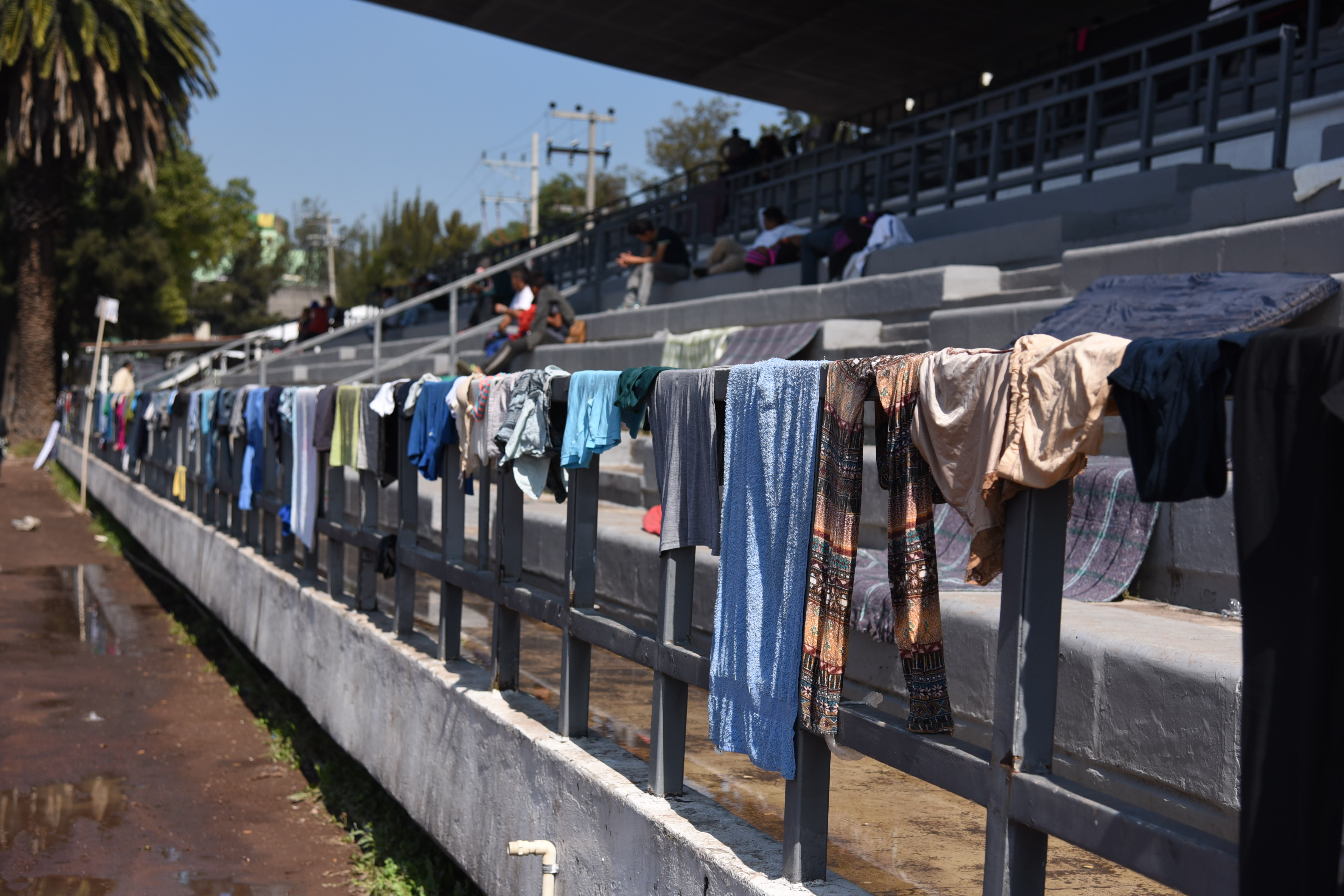 Rain-soaked clothing, given to Central American migrants who left home with only the garments on their backs, line a banister last week at a Mexico City soccer stadium. (Photo by Sam Fulwood/Think Progress)