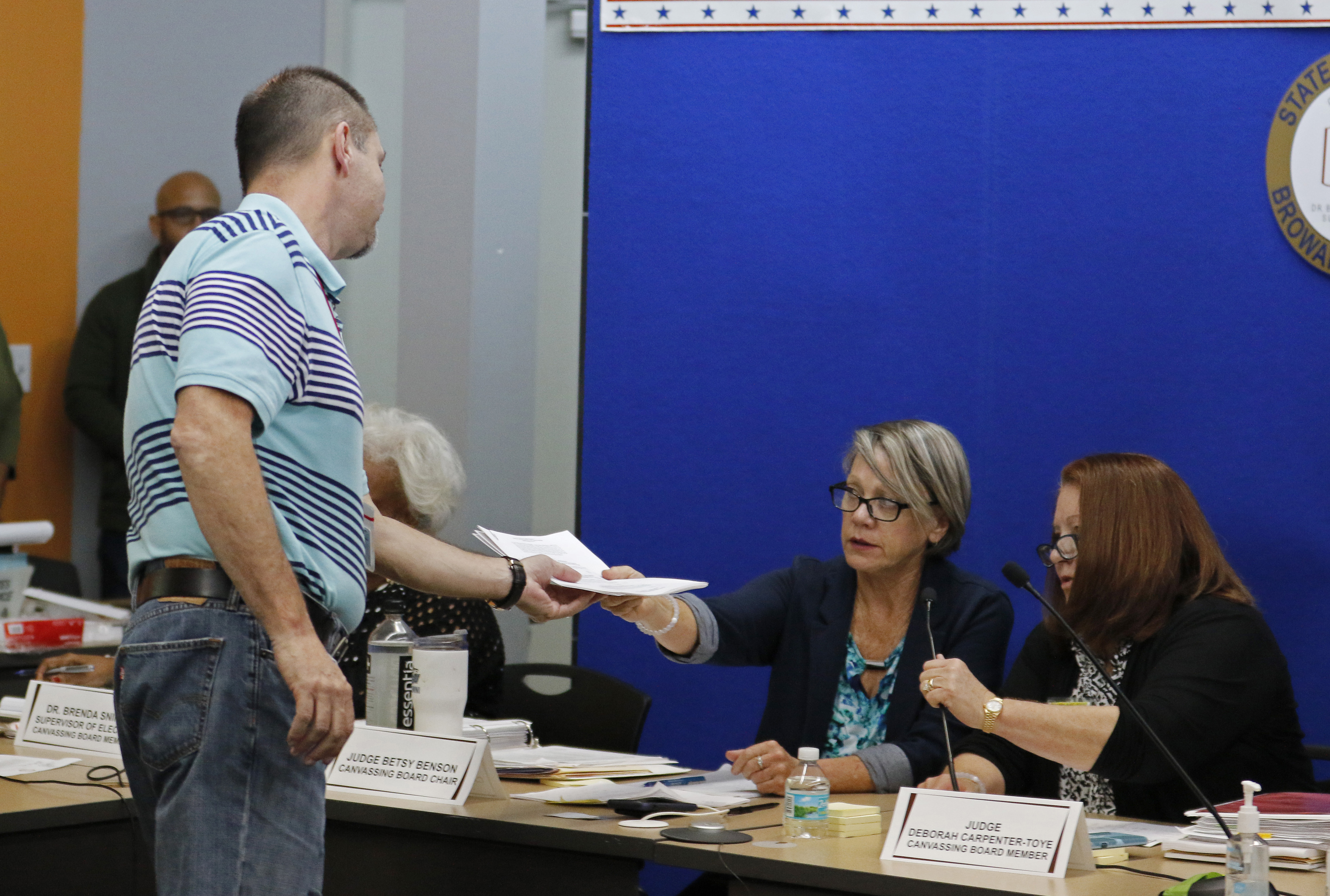 A member of the Canvassing Board of Broward County Supervisor of Elections hands signed results to an official after they were transmitted to the state capitol on November 10, 2018 in Lauderhill, Florida. Three close midterm election races for governor, senator, and agriculture commissioner will be recounted in Florida. (Photo Credit: Joe Skipper/Getty Images)