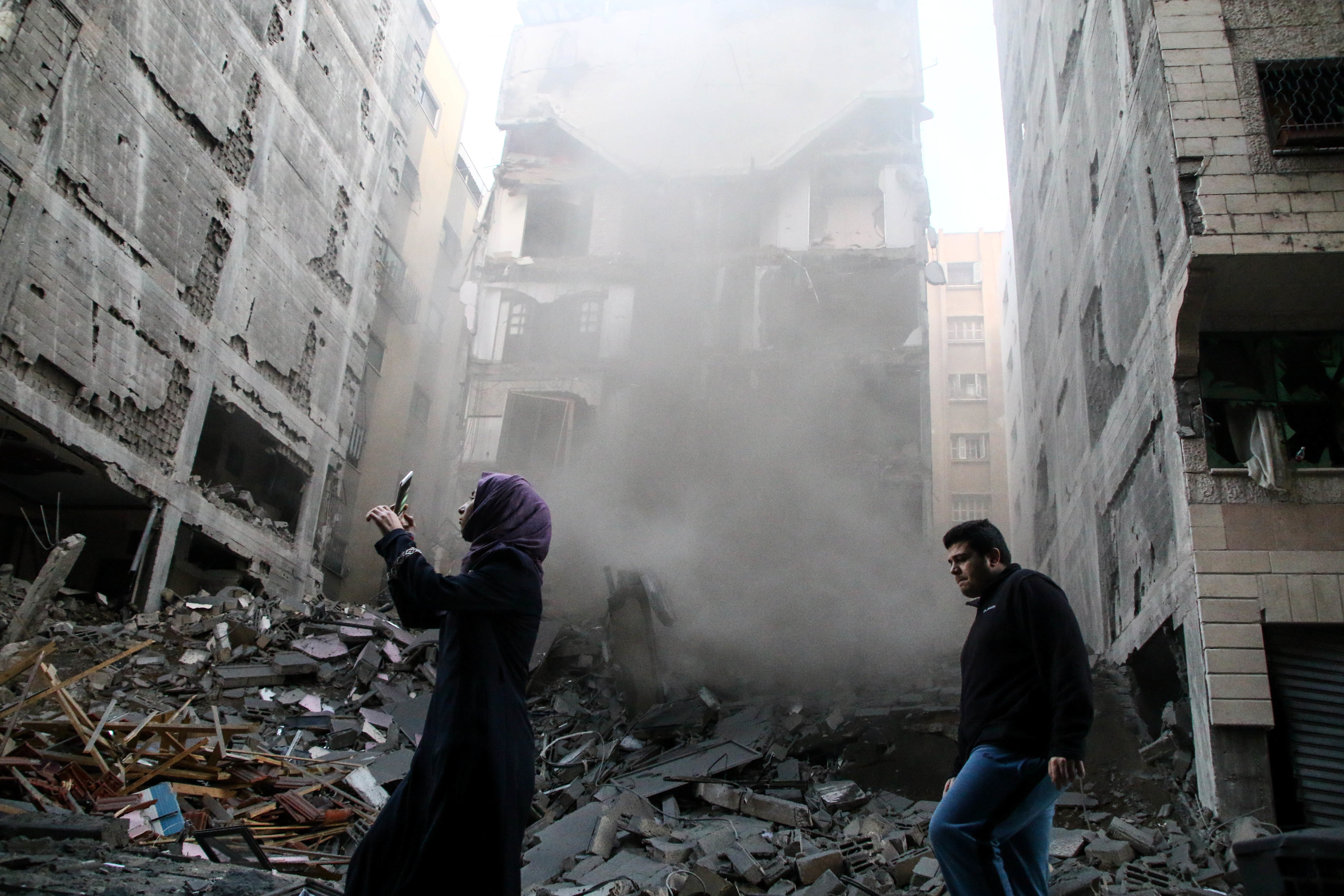 A woman and a man are seen walking on the ruins of the building of the Yazji family which was bombed by the Israeli planes during raids at the Gaza Strip on Nov. 13, 2018. CREDIT: Ahmad Hasaballah/SOPA Images/LightRocket via Getty Images.