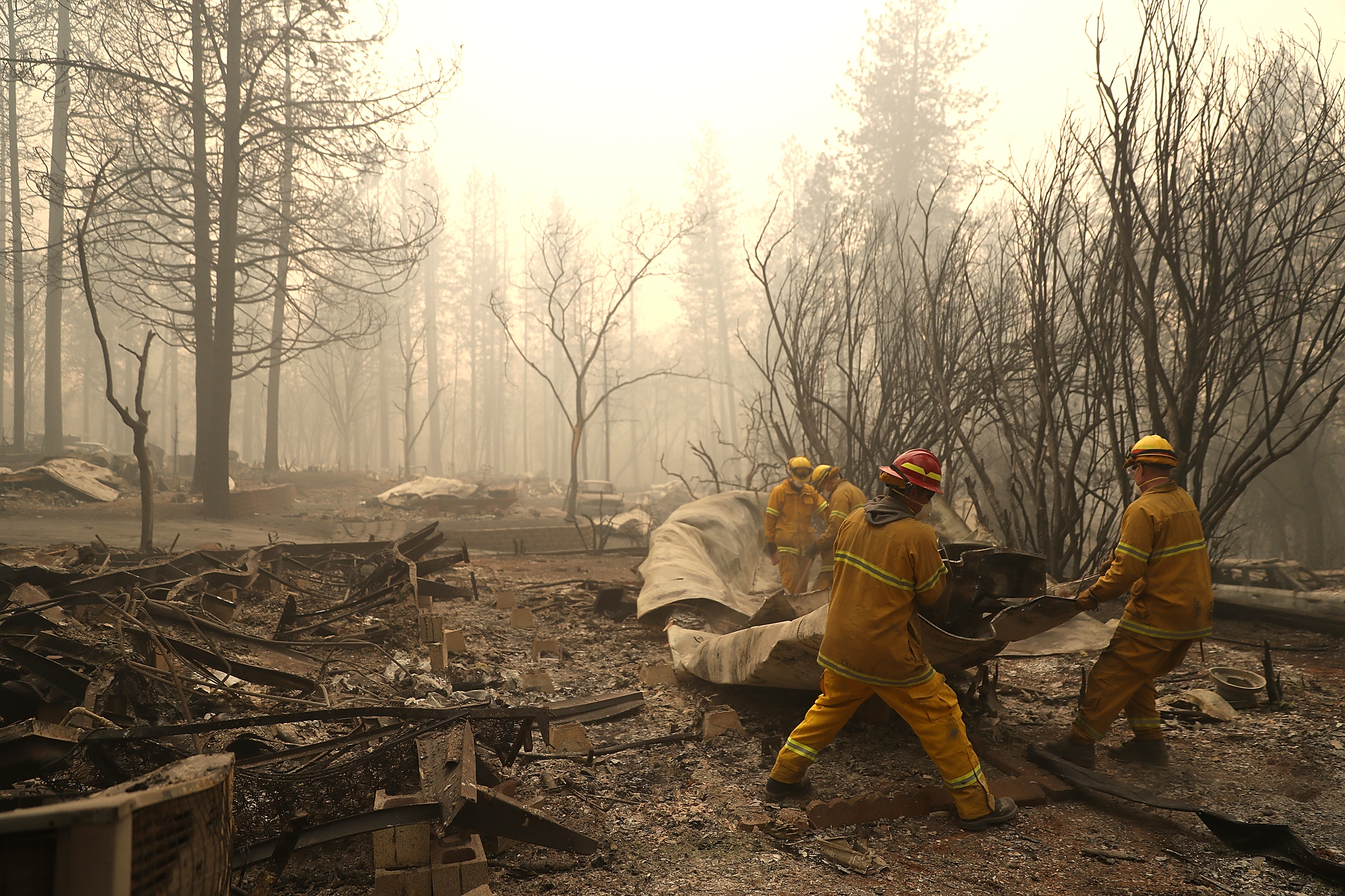 San Francisco firefighters dismantle a burned mobile home as they search for human remains at a mobile home park that was destroyed by the Camp Fire on November 14, 2018 in Paradise, California. CREDIT: Justin Sullivan/Getty Images