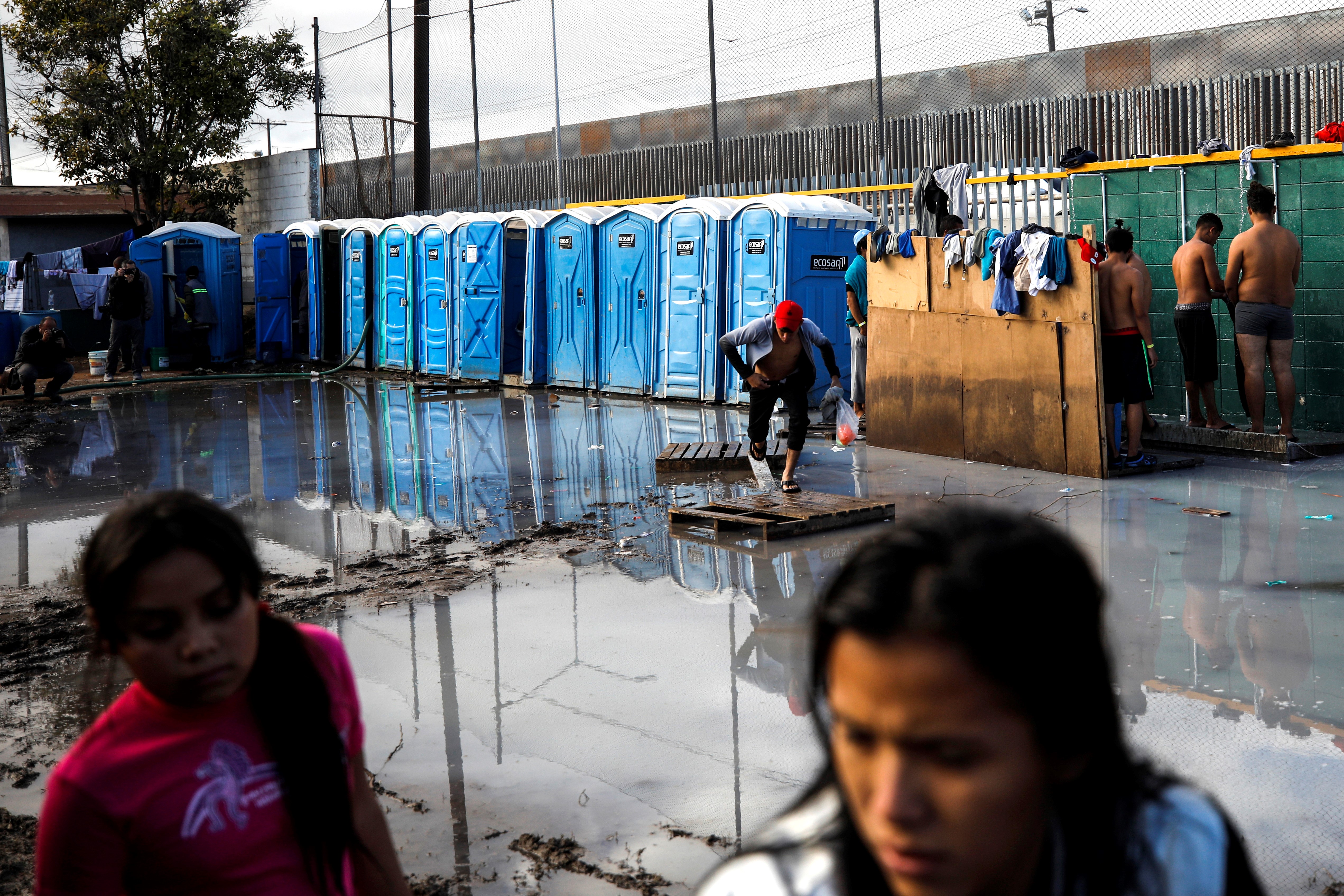 Migrants take showers over muddy pits at the Benito Juarez Sports complex on November 28, 2018. CREIT: Atilgan Ozdil/Anadolu Agency/Getty Images.