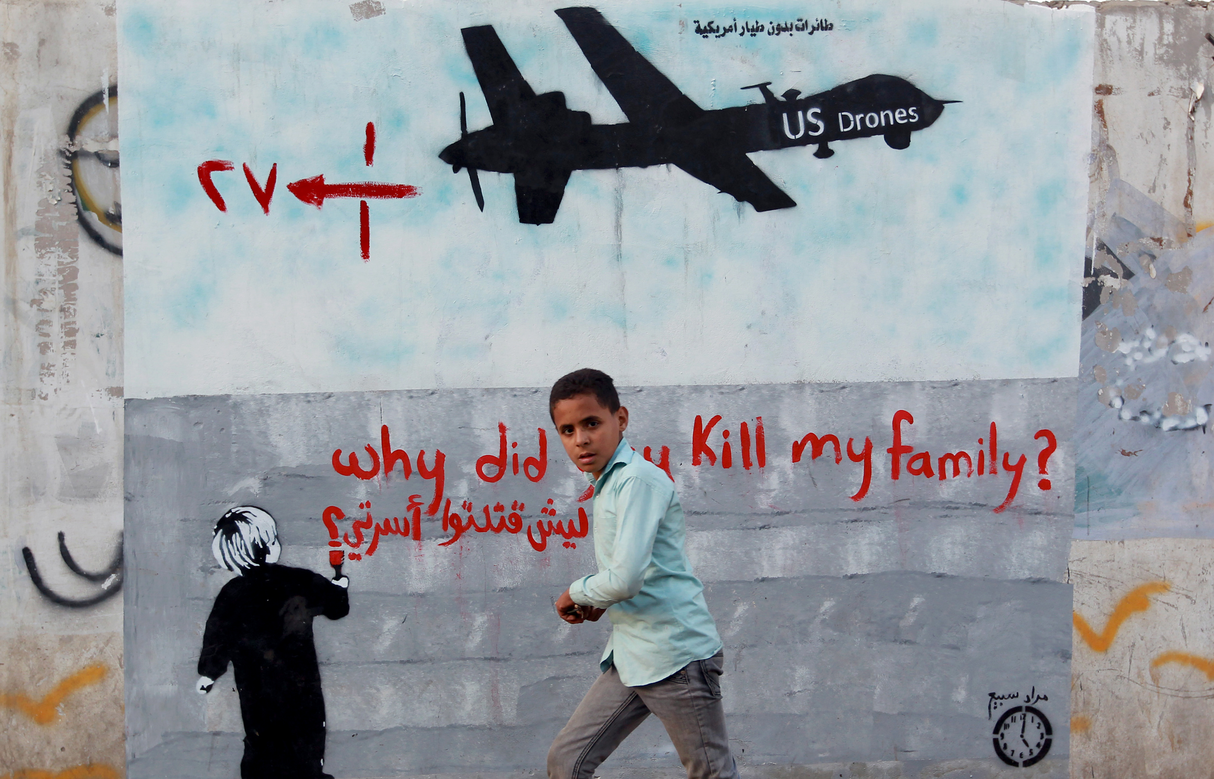 A Yemeni boy walks past a mural depicting a US drone in the capital Sanaa. CREDIT: Mohammed Huwais/AFP/Getty Images.