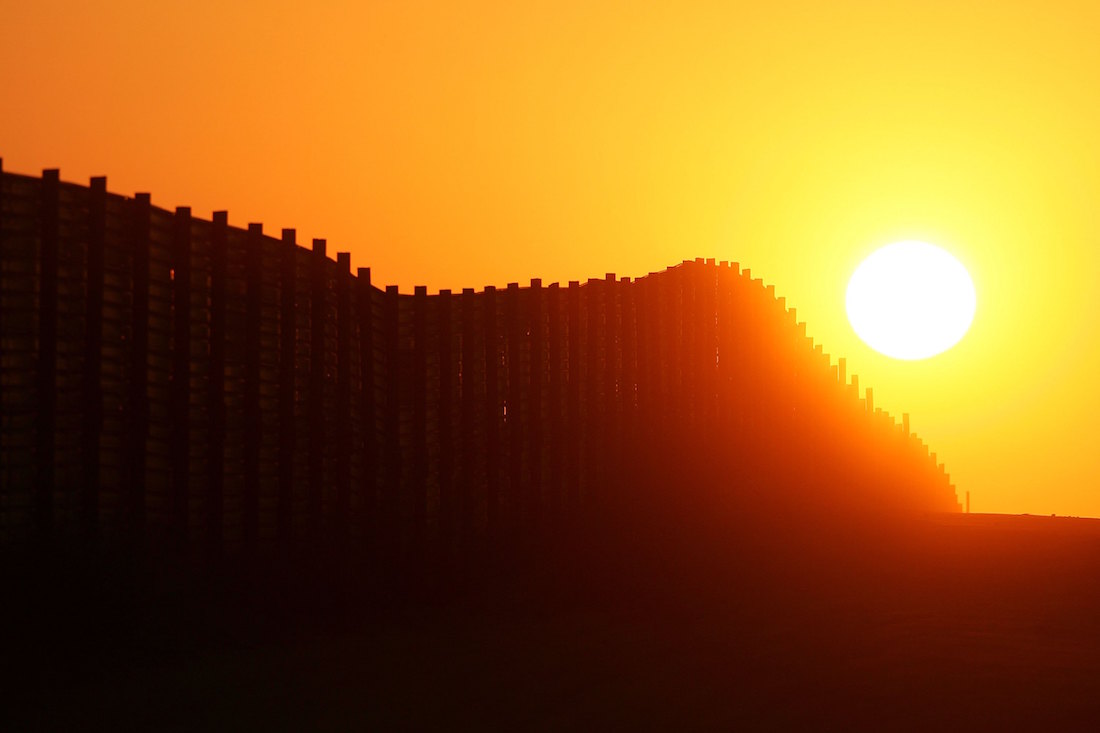 The sun sets behind a section of the U.S.-Mexico border fence in Campo, California on October 8, 2006. (David McNew/Getty Images)
