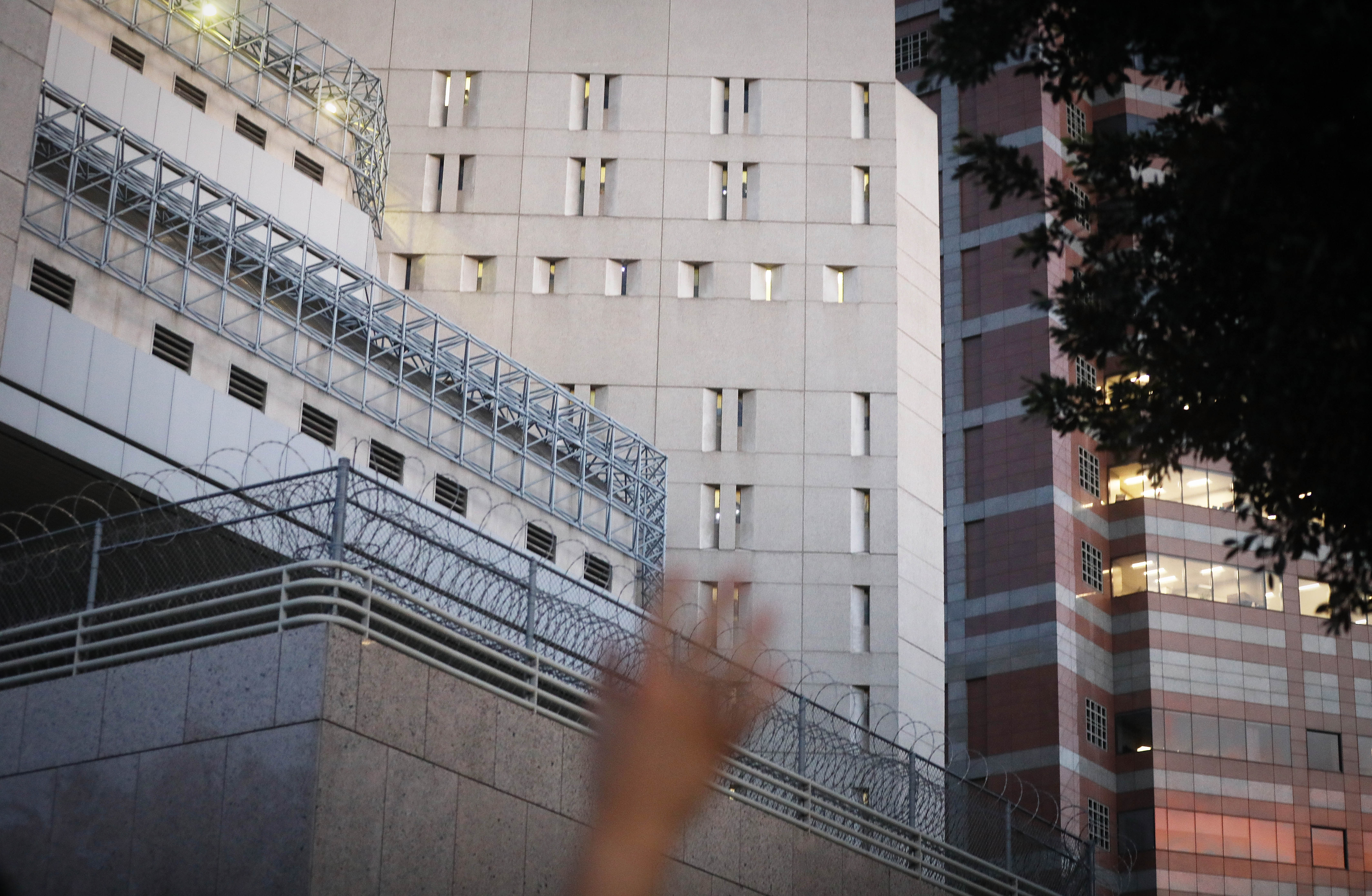 A protestor waves towards cell windows where ICE detainees are being held in upper floors of the Metropolitan Detention Center, in Los Angeles, California, on June 14, 2018. CREDIT: Mario Tama/Getty Images