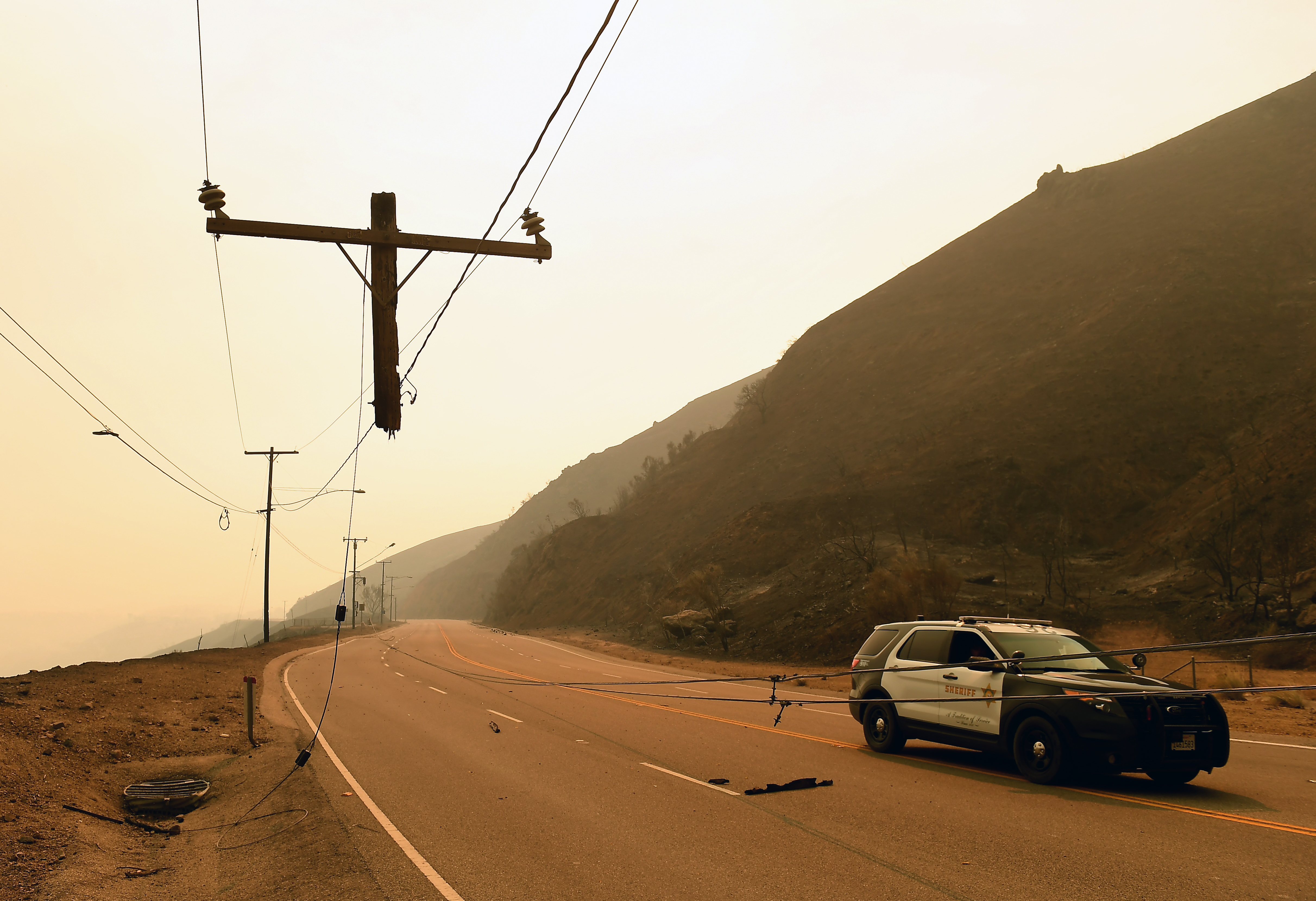 A sheriff's vehicle passes downed power lines after the Woolsey Fire roared through Malibu, California on November 10, 2018 in Malibu, California. CREDIT: Wally Skalij/Los Angeles Times via Getty Images