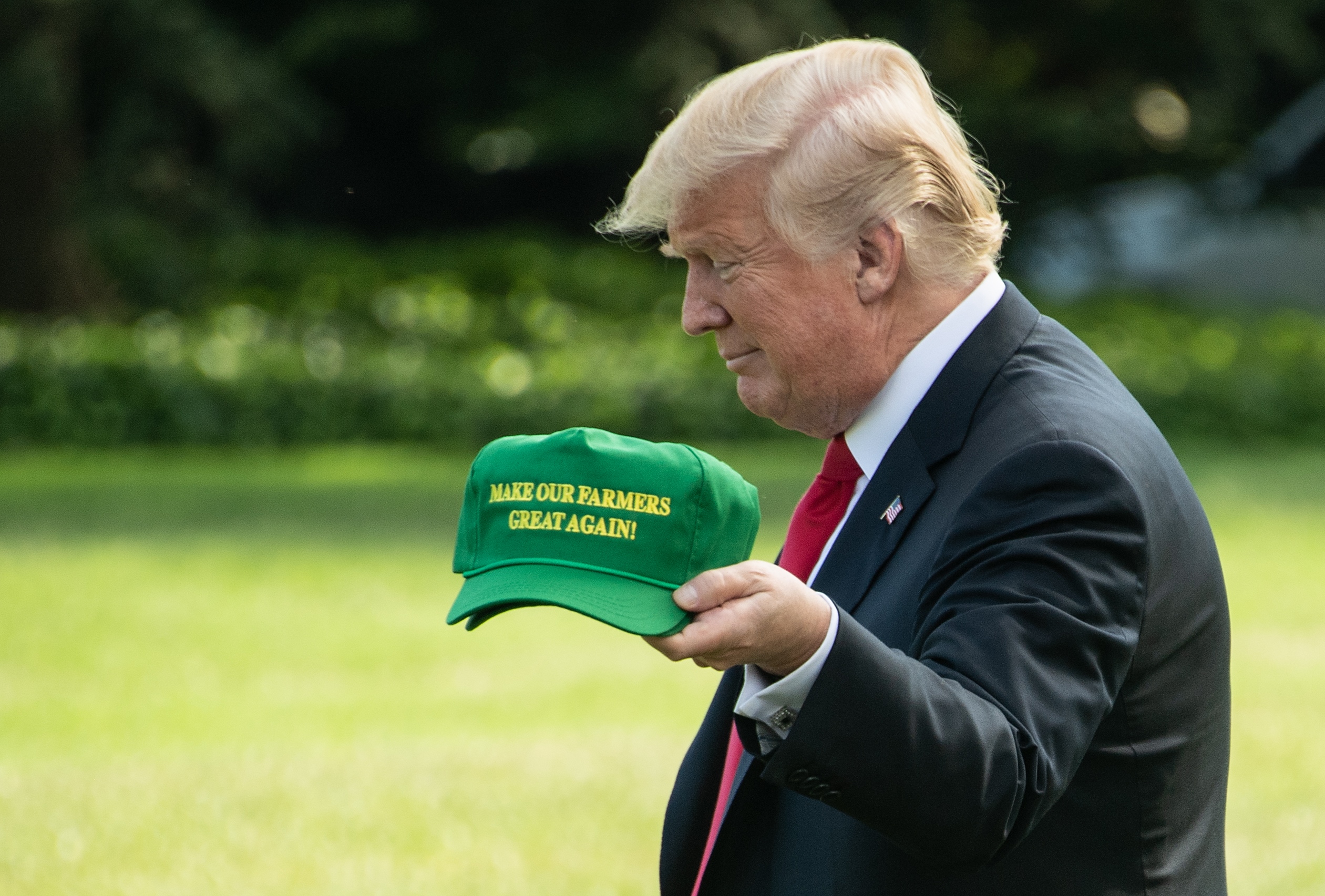 US President Donald Trump displays caps reading "Make our Farmers Great Again" while walking to board Marine One as he departs the White House in Washington, DC, on August 30, 2018 for Indiana. (Photo by NICHOLAS KAMM / AFP) (Photo credit should read NICHOLAS KAMM/AFP/Getty Images)