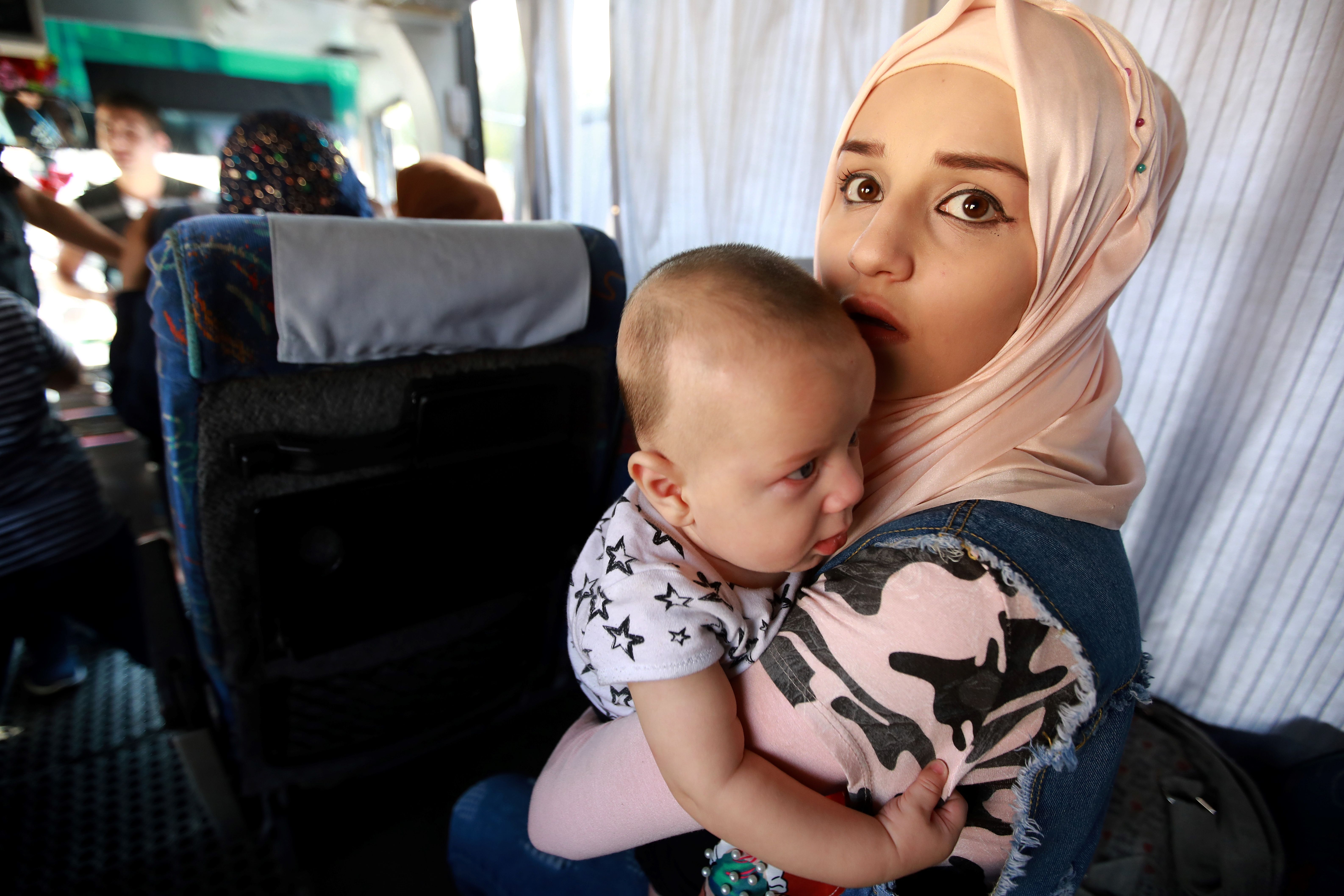 A Syrian woman holds a toddler in her arms inside a bus as refugees prepare to leave the Lebanese capital Beirut to return to their homes in Syria on September 9, 2018. CREDIT: Anwar Amro/AFP/ Getty Images.