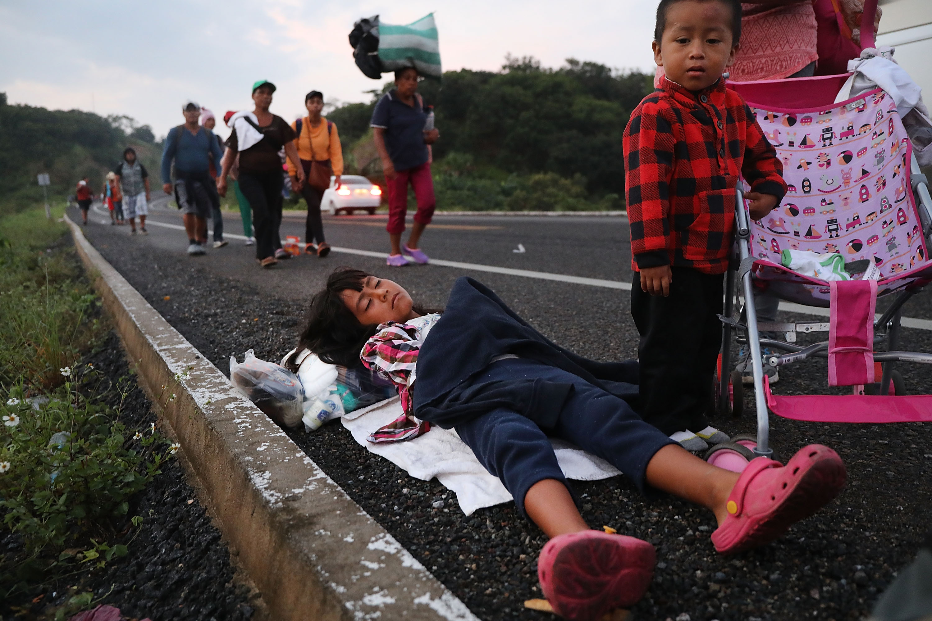 Sesar, 6, sleeps along the road with her family as members of the Central American migrant caravan move to the next town in the pre-dawn hours on November 02, 2018 in Matias Romero, Mexico. (Photo Credit: Spencer Platt/Getty Images)