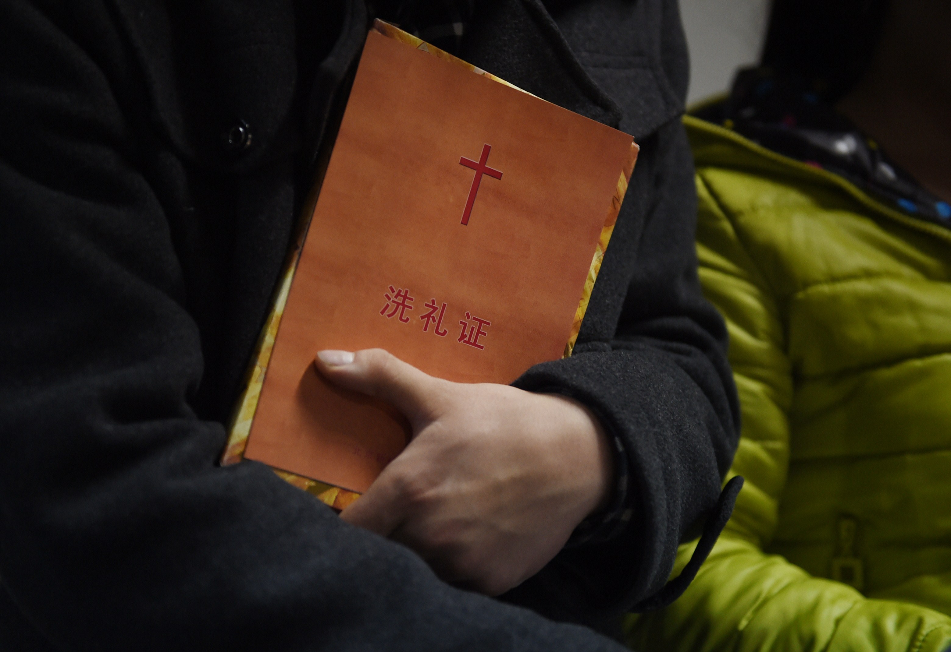 This photo taken on December 24, 2014 shows a man holding a certificate of baptism after he was baptized during a Christmas Eve service held by members of an underground church, at an apartment in Beijing. CREDIT: Greg Baker/AFP/Getty Images.
