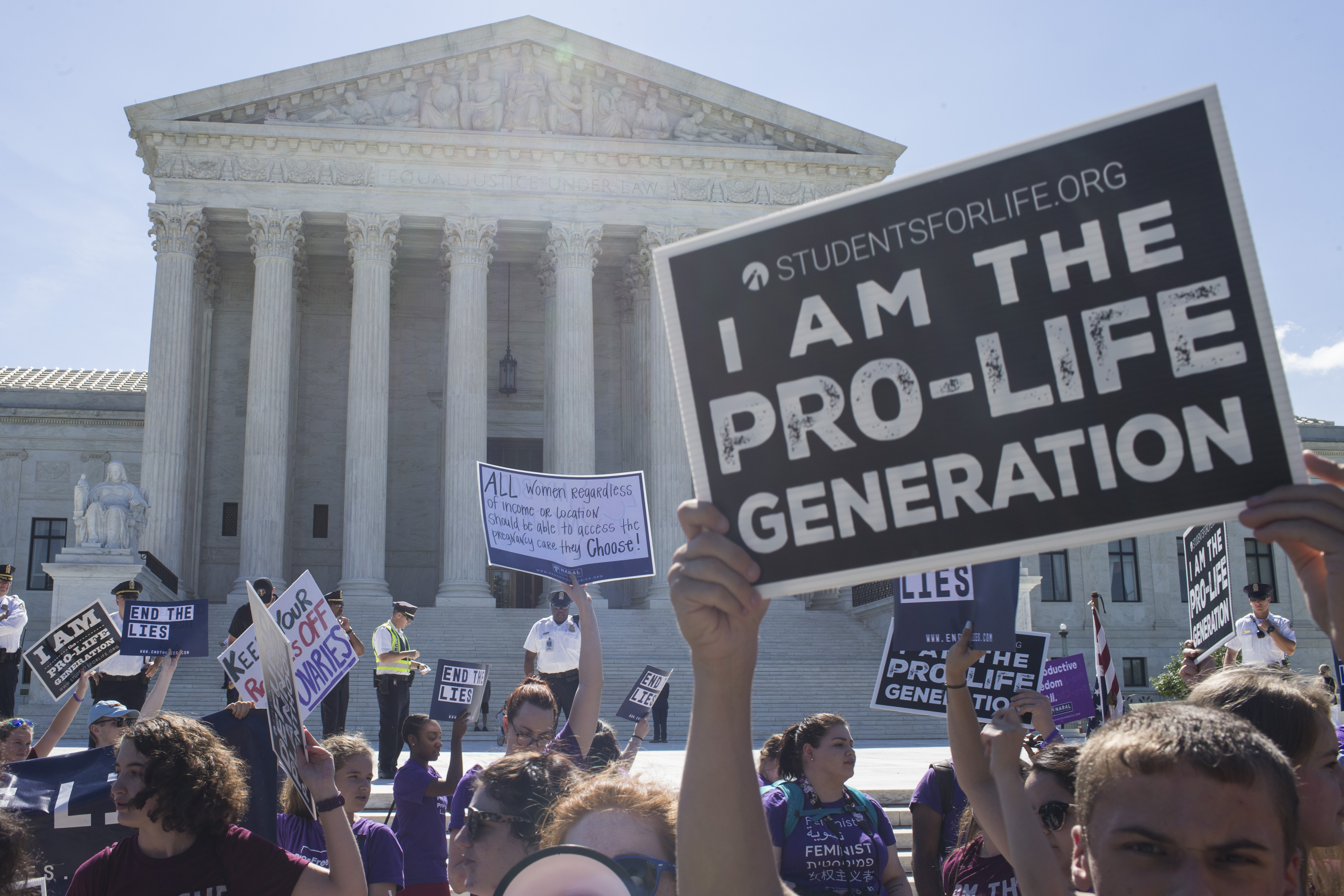 WASHINGTON, DC - JUNE 25: Abortion opponents and supporters hold signs in front of the U.S. Supreme Court on June 25, 2018 in Washington, DC. The high court is expected to issue decisions in six remaining cases, including the travel ban, public sector unions and redistricting, ahead of their end-of-June deadline this week. (Photo by Zach Gibson/Getty Images)