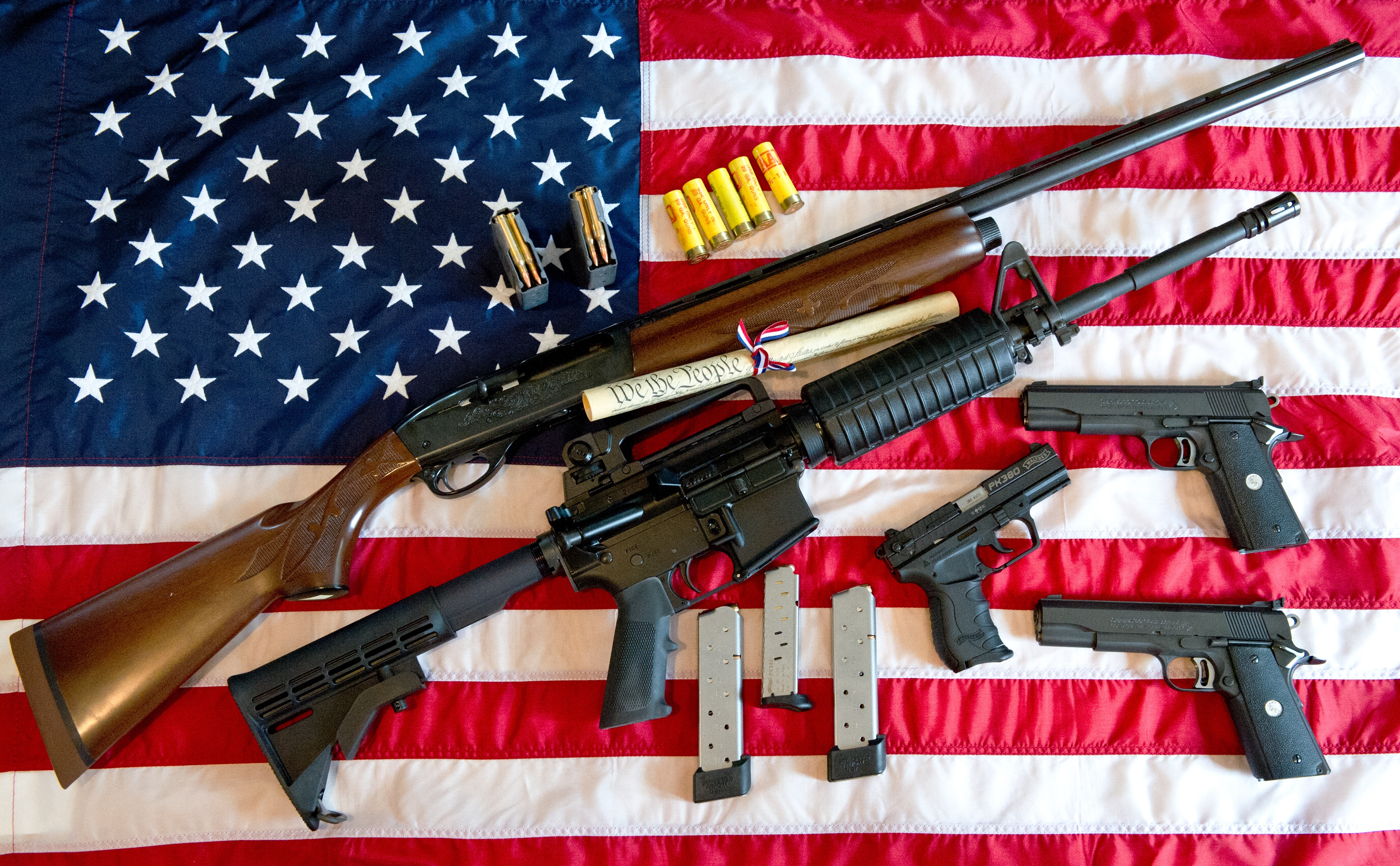 A Remington 20-gauge semi-automatic shotgun, a Colt AR-15 semi-automatic rifle, a Colt .45 semi-auto handgun, a Walther PK380 semi-auto handgun, and various ammunition clips with a copy of the U.S. Constitution in Manassas, Virginia on February 4, 2013. (KAREN BLEIER/AFP/Getty Images)