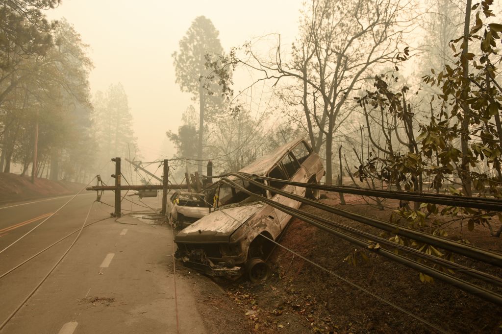 A fallen power line is seen on top of burnt out vehicles on the side of the road in Paradise, California after the Camp fire tore through the area on November 10, 2018. (Credit: JOSH EDELSON/AFP/Getty Images)