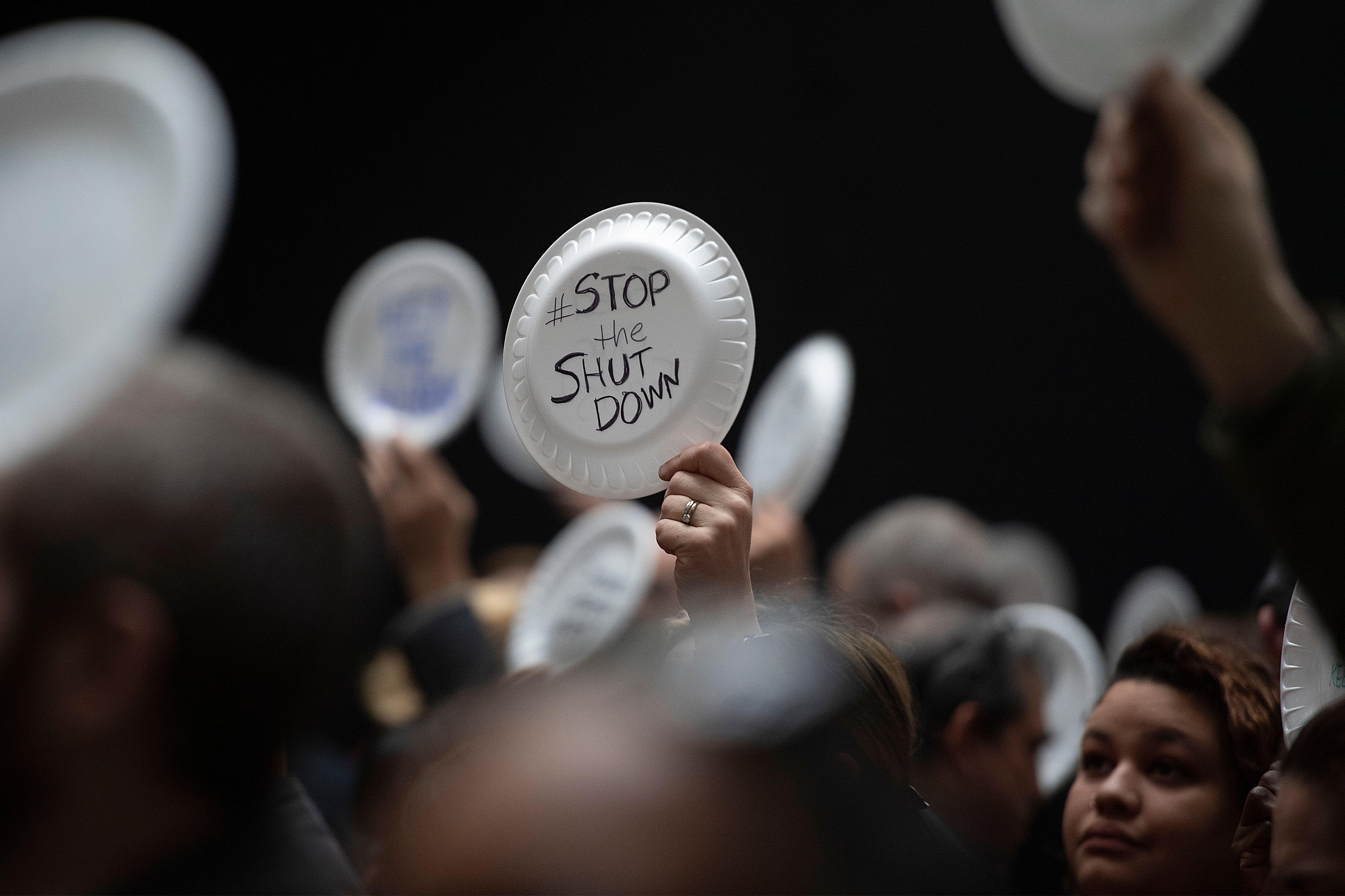 A federal worker stands with a placard reading "Stop the Shut Down" as other federal employees stage a rally to call for a vote on the shutdown on Capitol Hill in Washington, DC, on January 23, 2019. (Photo Credit: JIM WATSON/AFP/Getty Images)