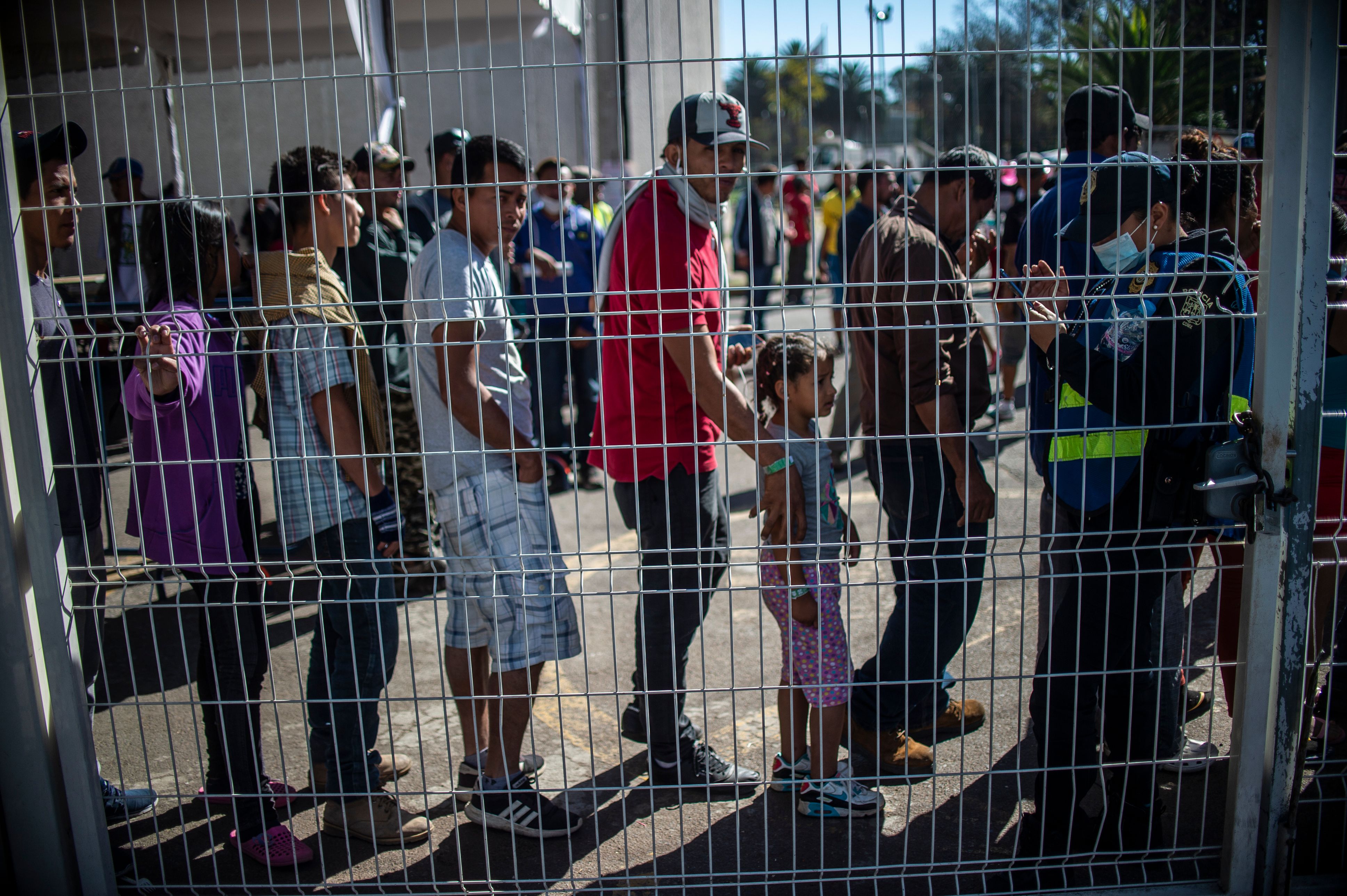 Central American migrants - mostly Hondurans - taking part in a caravan heading towards the US, queue to enter a shelter set up at the Sports City in Mexico City on January 30, 2019. CREDIT: Pedro Pardo/AFP/Getty Images.
