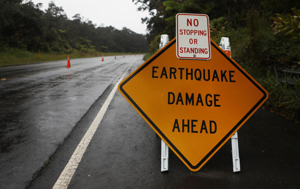 A sign is posted warning of earthquake damage to the road from seismic activity at the Kilauea volcano on Hawaii's Big Island on May 17, 2018 in Hawaii Volcanoes National Park, Hawaii. (Credit: Mario Tama/Getty Images)