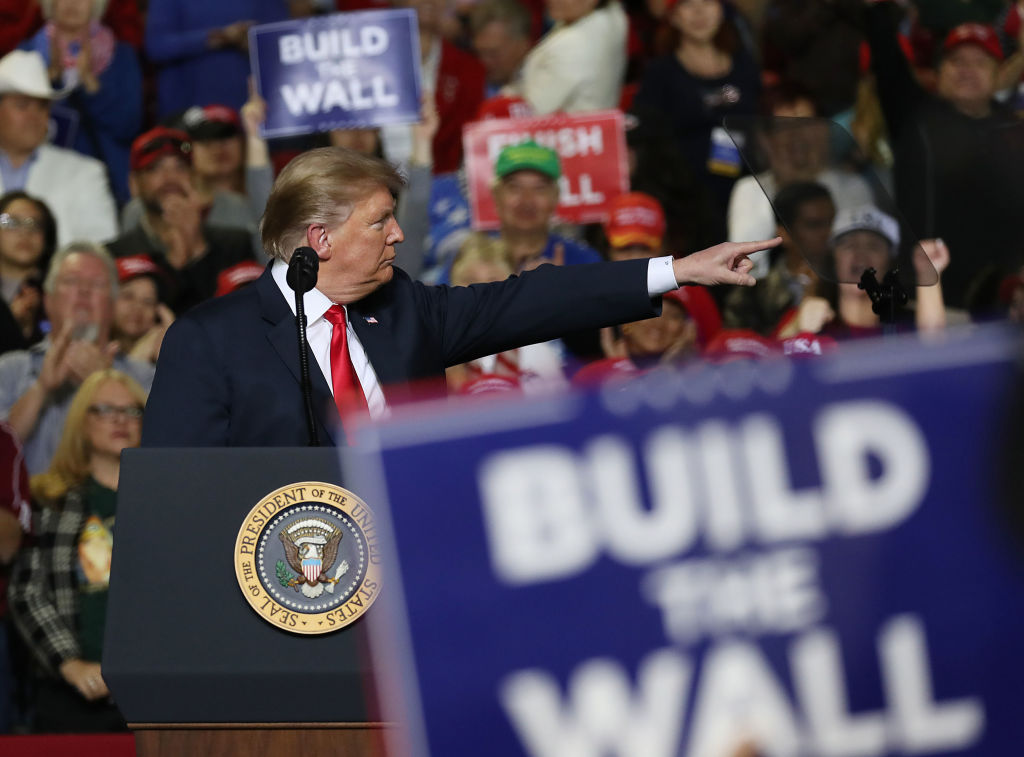 Donald Trump speaks during a rally in El Paso, Texas on Monday, while supporters hold contradictory signs.