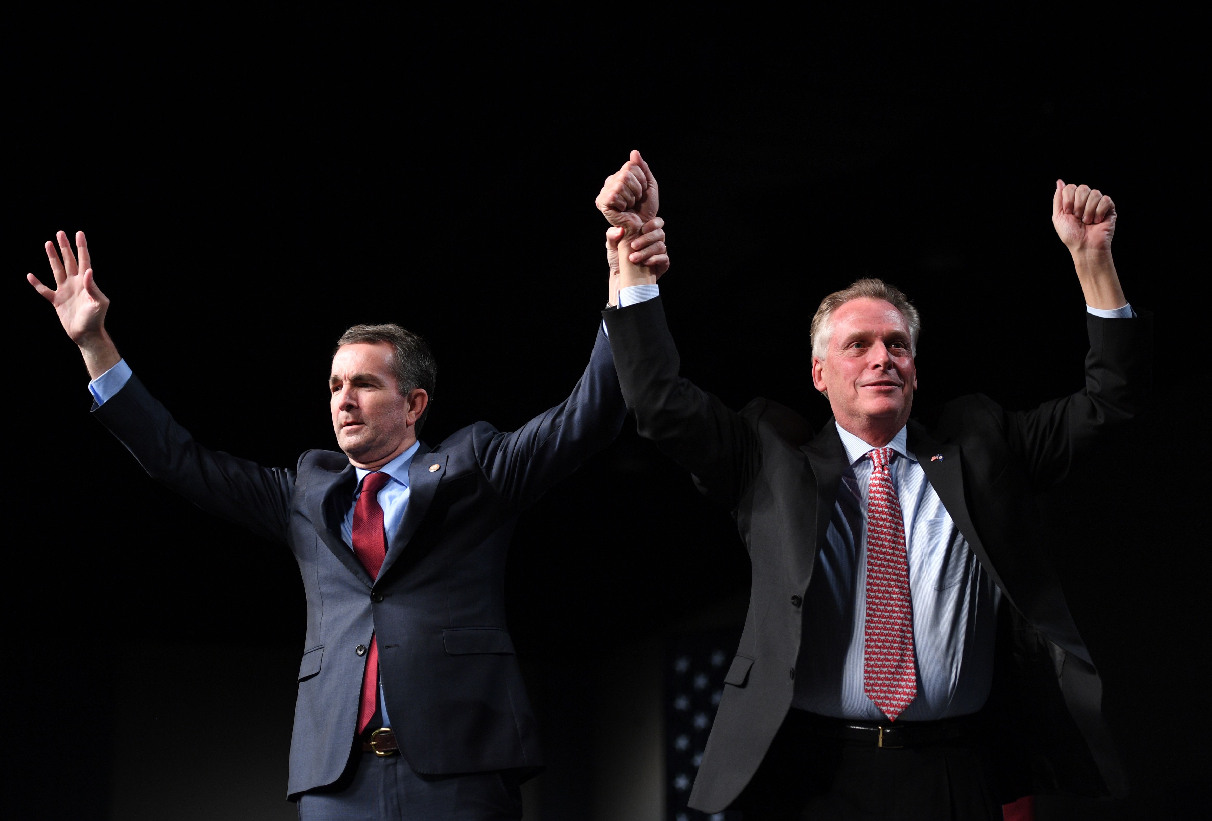 Virginia Governor Terry McAuliffe (R) holds up the hands of Democratic Gubernatorial Candidate Ralph Northam during a campaign rally in Richmond, Virginia October 19, 2017. (Credit: JIM WATSON/AFP/Getty Images)
