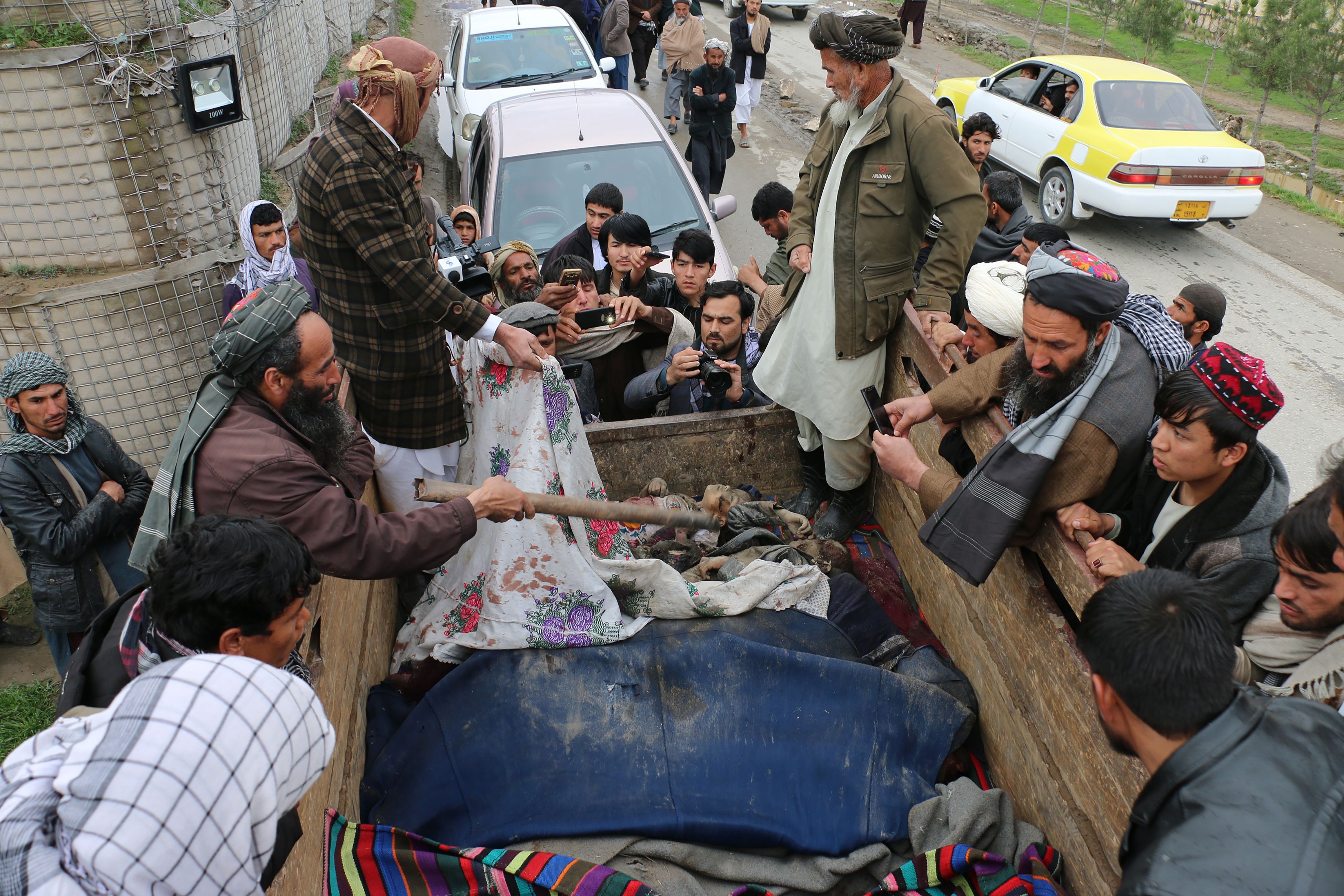 In this picture taken on March 23, 2019 Afghan men uncover the dead bodies of young children laying in the back of a truck, after being killed in an air strike in Kunduz Province. CREDIT: Bashir Khan Safi/AFP/Getty Images.