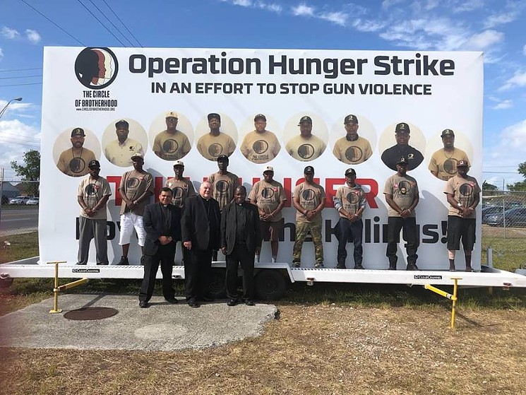 The Hunger Nine, posed in front of their sign at their campsite. (Photo cred: Lyle Muhammad/Circle of Brotherhood)