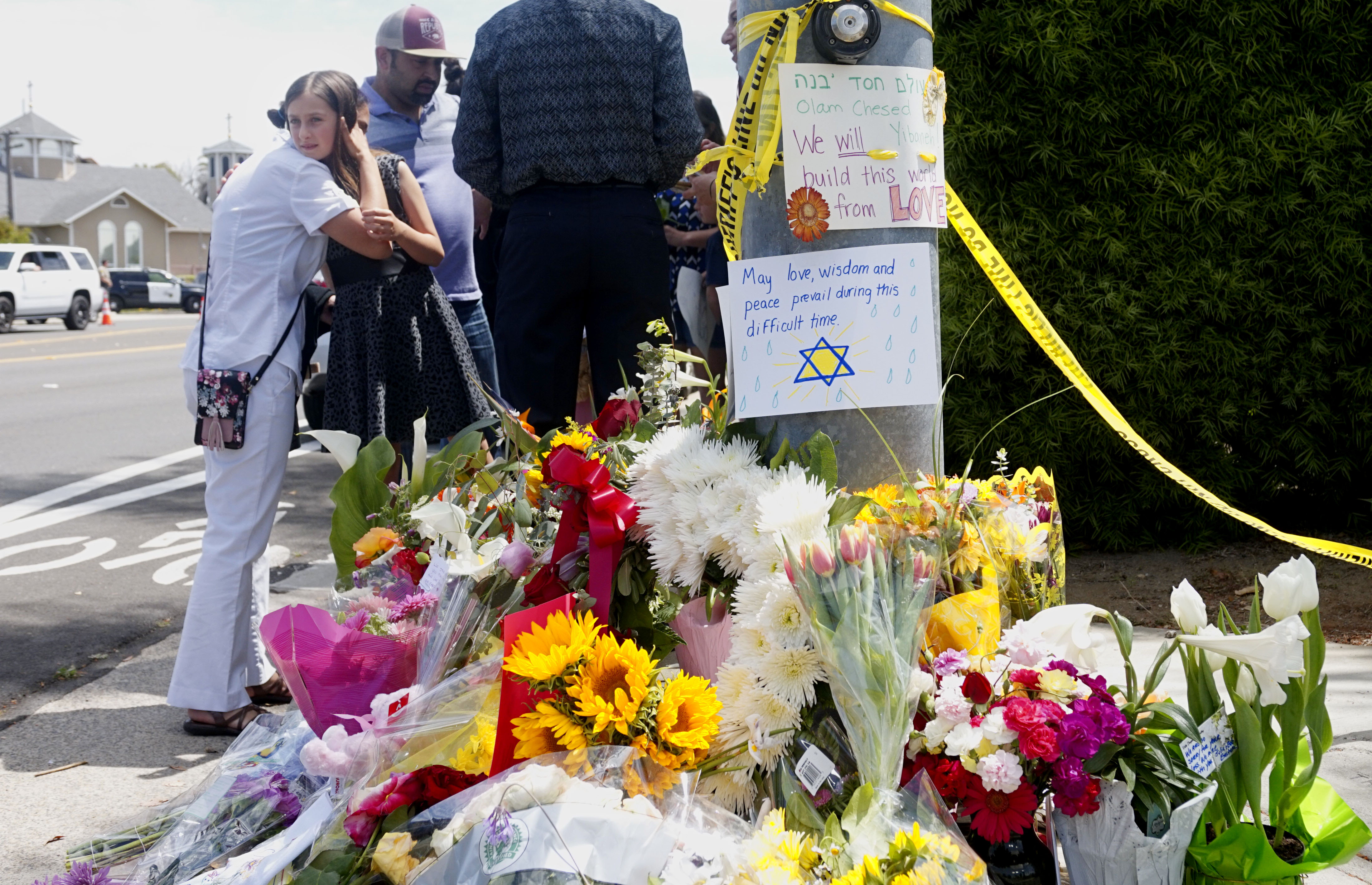 Mourners and well wishers leave flowers and signs at a make-shift memorial across the street from the Chabad of Poway Synagogue on Sunday, April 28, 2019 in Poway, California. (Photo credit should read SANDY HUFFAKER/AFP/Getty Images)