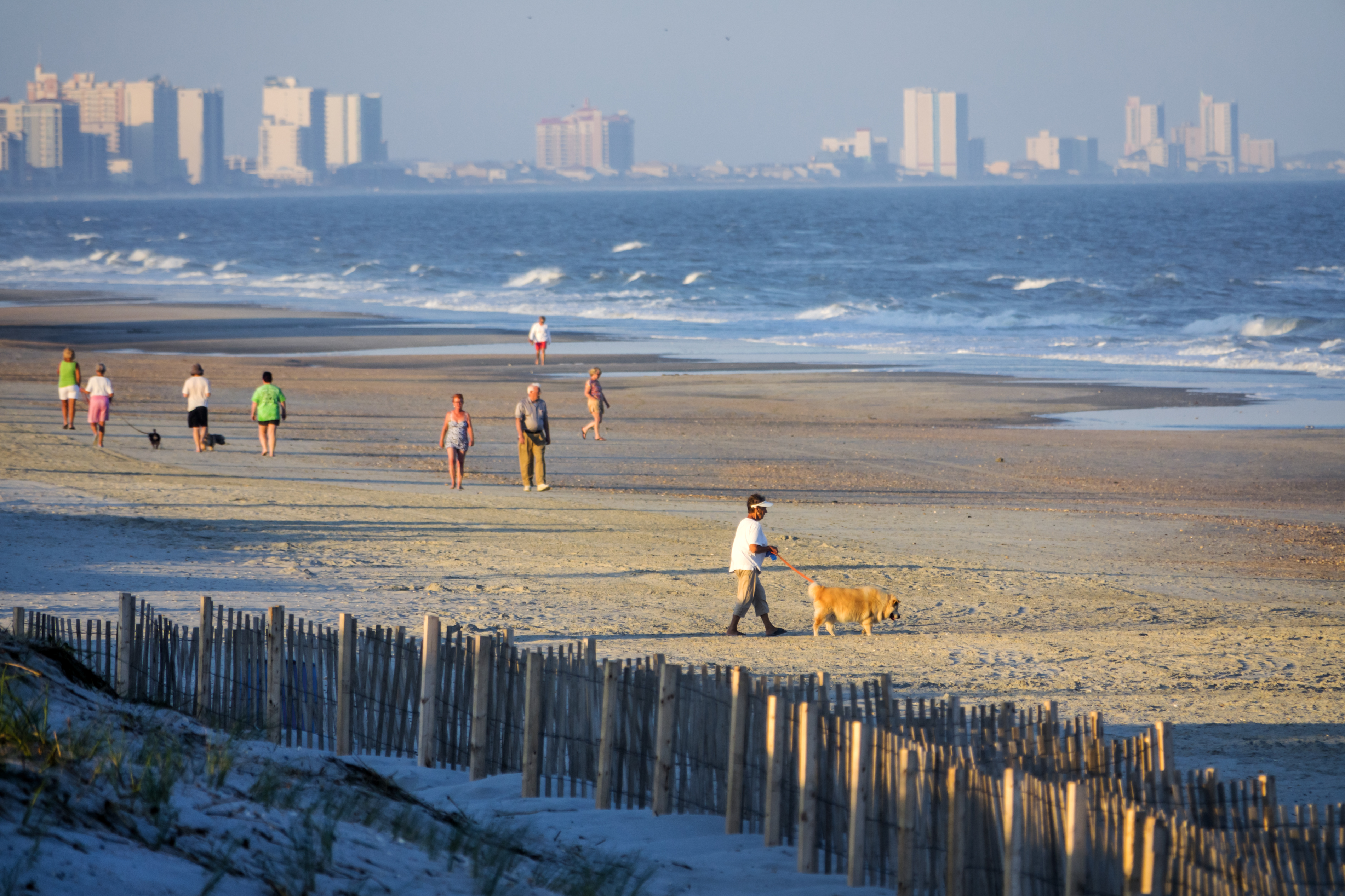 South Carolina, Atlantic Ocean, Myrtle Beach, beachcombers walking dog. CREDIT: Jeffrey Greenberg/UIG via Getty Images