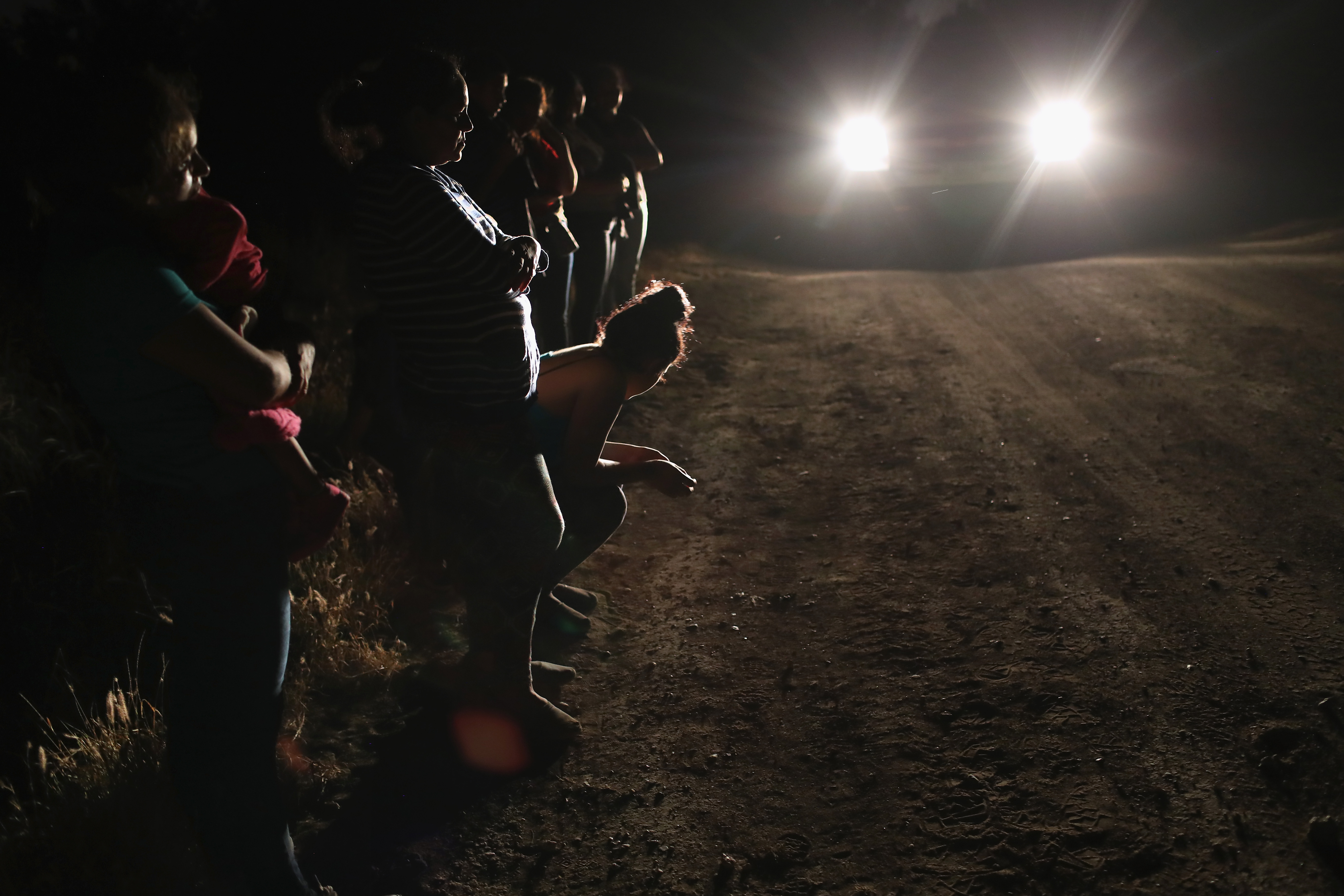 Central American asylum seekers, including a Honduran girl, 2, and her mother (L), are taken into custody near the U.S.-Mexico border on June 12, 2018 in McAllen, Texas. The group of women and children had rafted across the Rio Grande from Mexico and were detained by U.S. Border Patrol agents before being sent to a processing center for possible separation. (Photo Credit: John Moore/Getty Images)
