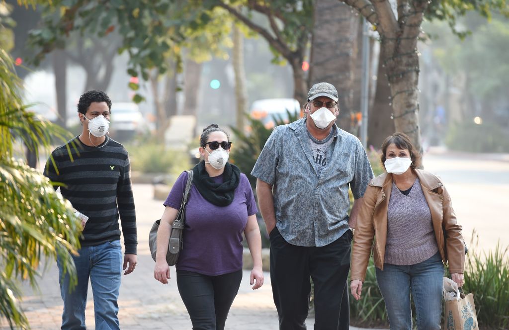 Visitors wearing masks walk to protect themselves from smoke and ash from the Thomas Fire walk on State Street, the main shopping street in Santa Barbara, California, December 12, 2017. (Credit: ROBYN BECK/AFP/Getty Images)