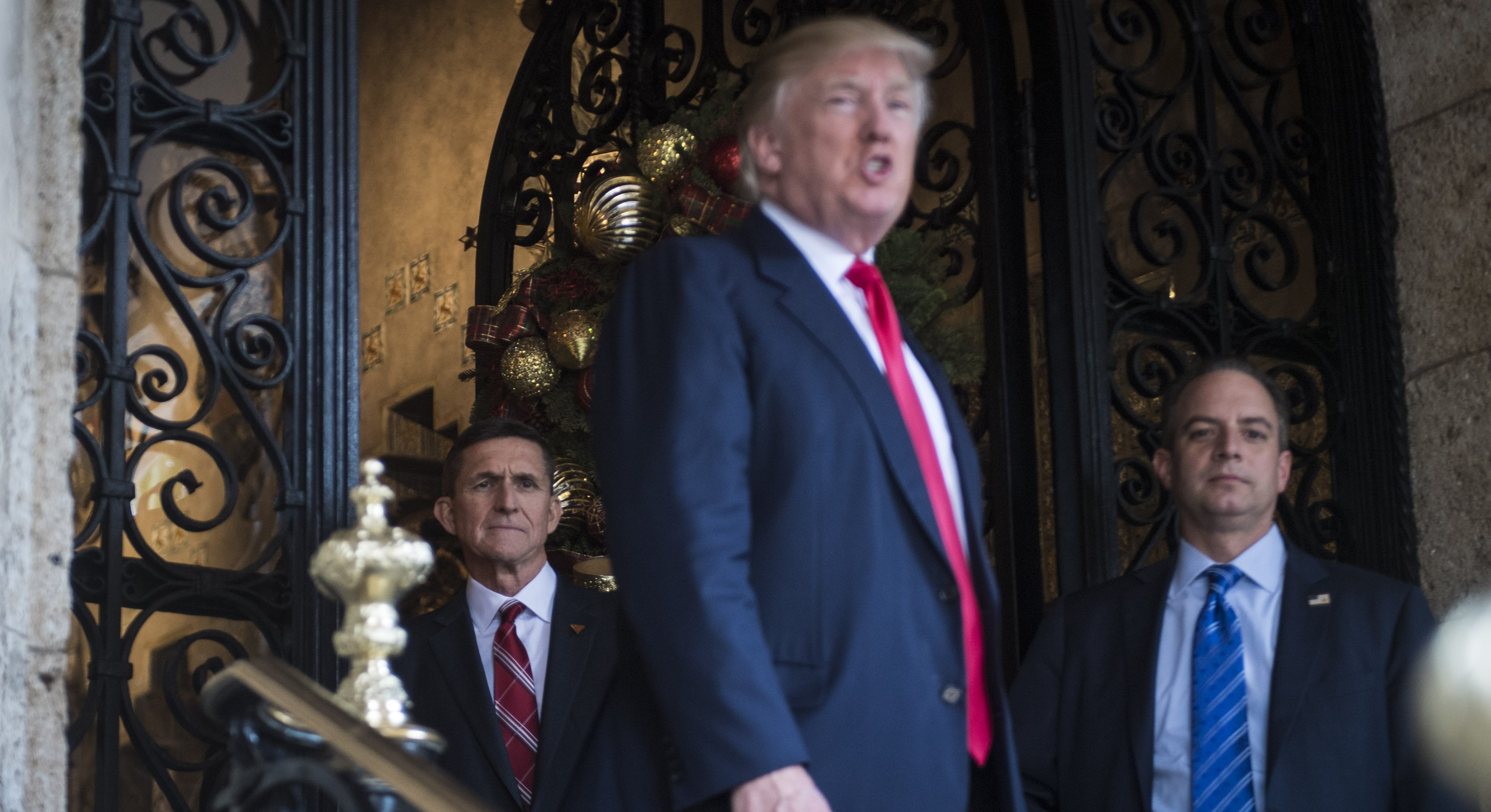 Former National Security Advisor Michael Flynn, left, and former White House Chief of Staff Reince Priebus watch on as then President-elect Donald Trump speaks to reporter at the Mar-a-Lago club in Palm Beach, Florida, on Dec. 21, 2016. CREDIT: Jabin Botsford/The Washington Post via Getty Images