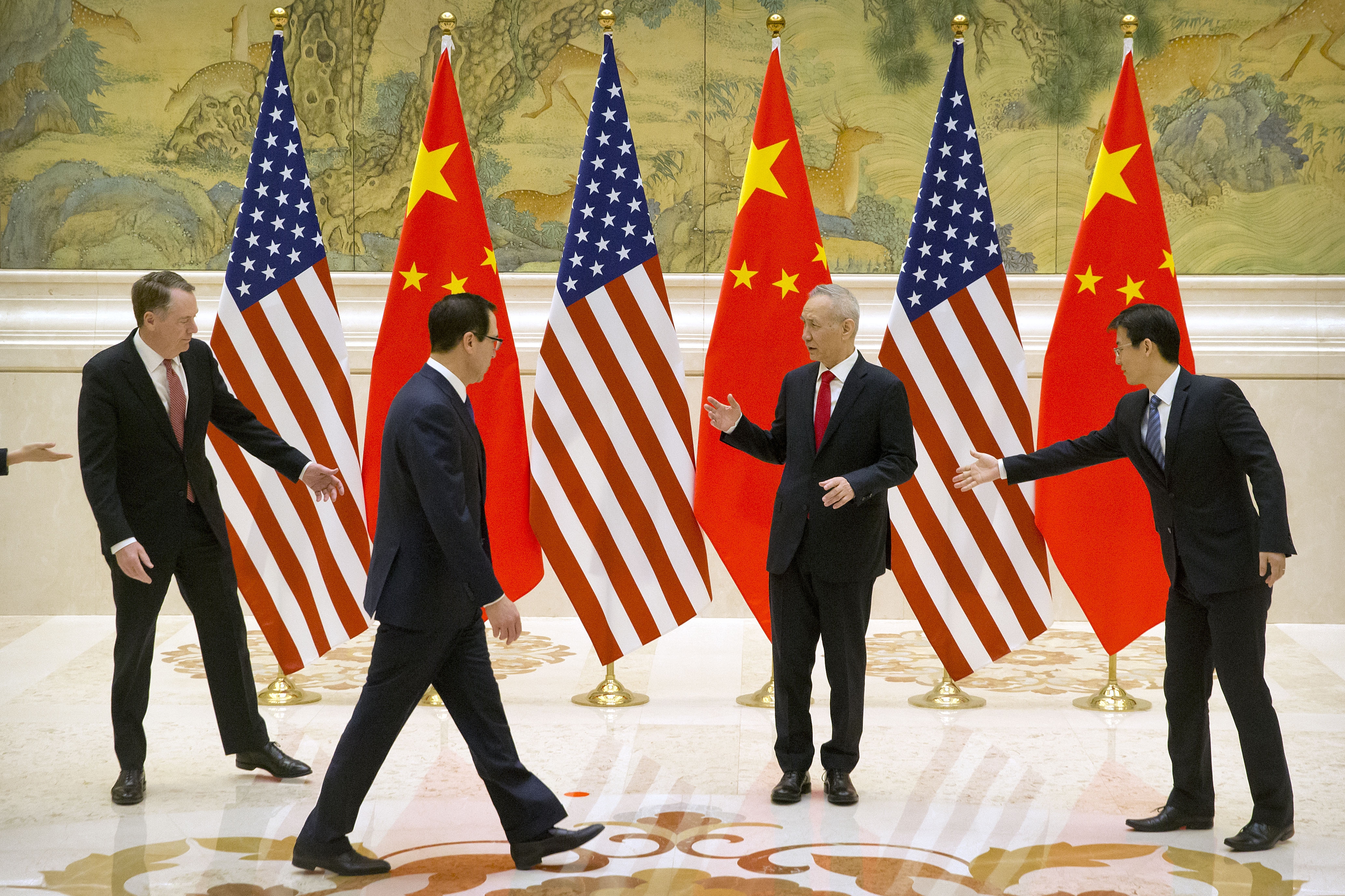 An aide (R) gestures as (from L) US Trade Representative Robert Lighthizer, Chinese Vice Premier and lead trade negotiator Liu He and US Treasury Secretary Steven Mnuchin line up for a photo in Beijing on February 14, 2019. CREDIT: MARK SCHIEFELBEIN/AFP/Getty Image.