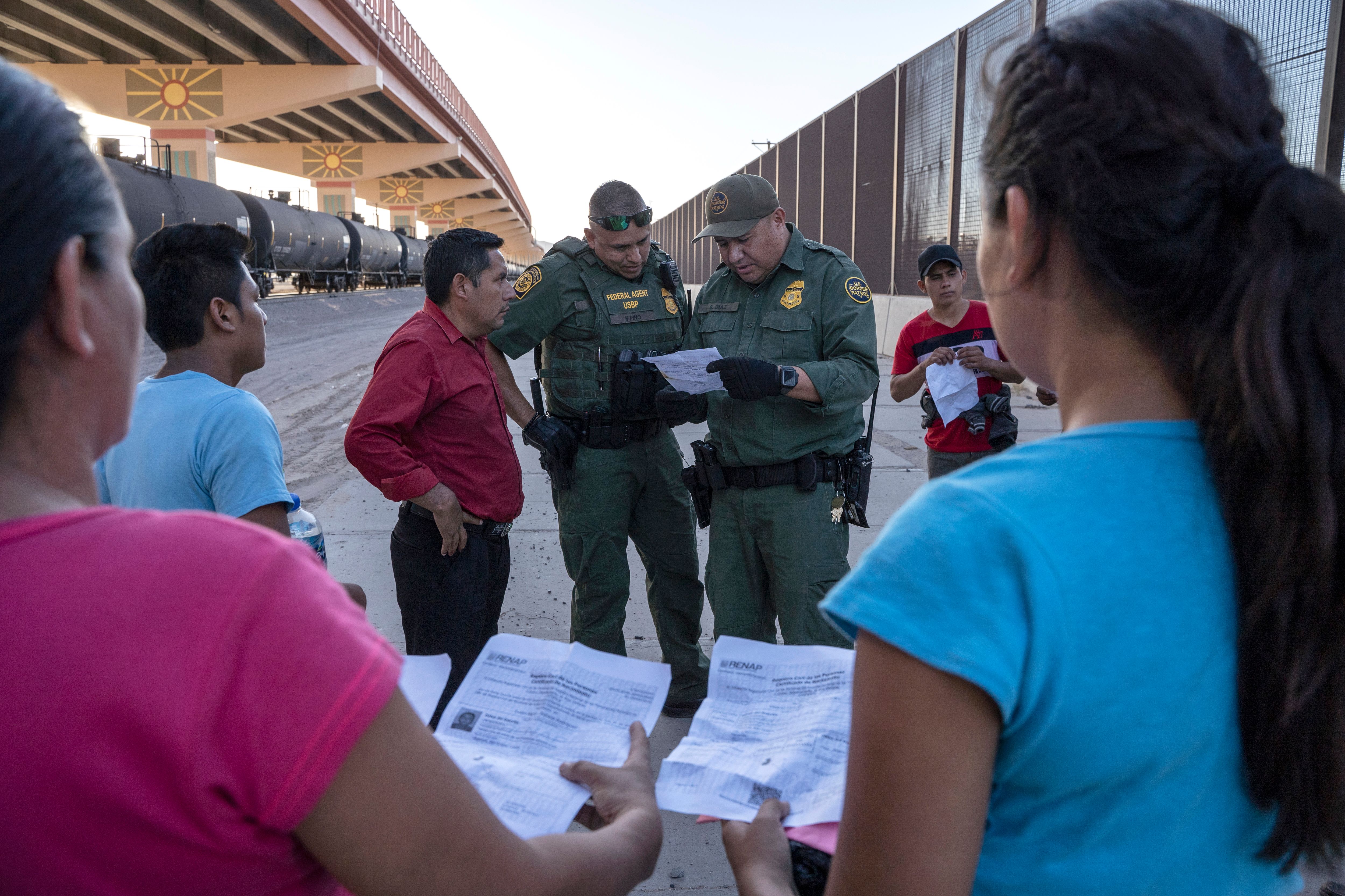 US Customs and Border Protection agents check documents of a small group of migrants, who crossed the Rio Grande from Juarez, Mexico, on May 16, 2019, in El Paso, Texas. (PAUL RATJE/AFP/Getty Images)