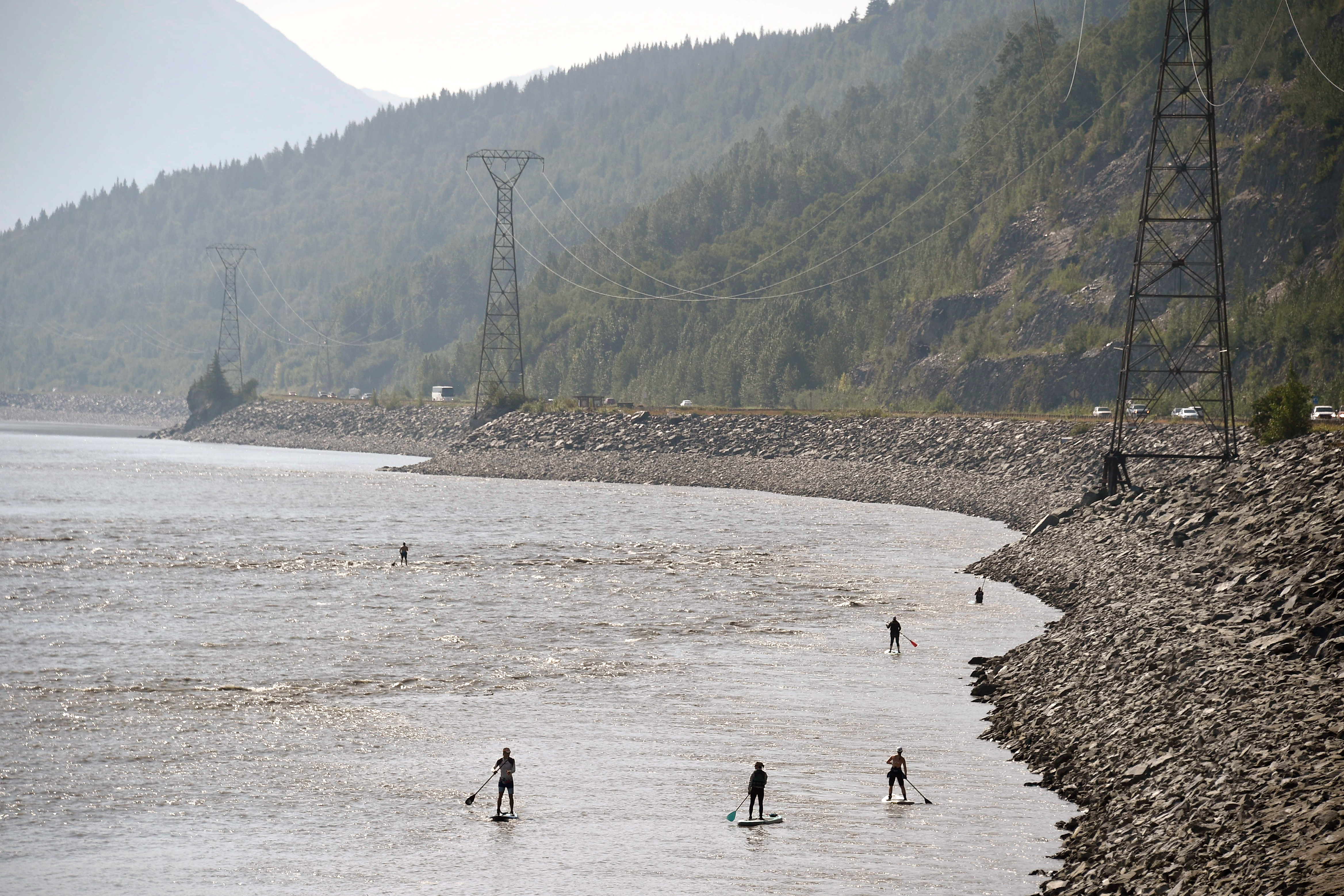 People navigate the Turnagain Arm on paddle boards as vehicles move along the Seward Highway on July 4, 2019 south of Anchorage, Alaska. (Photo by Lance King/Getty Images)