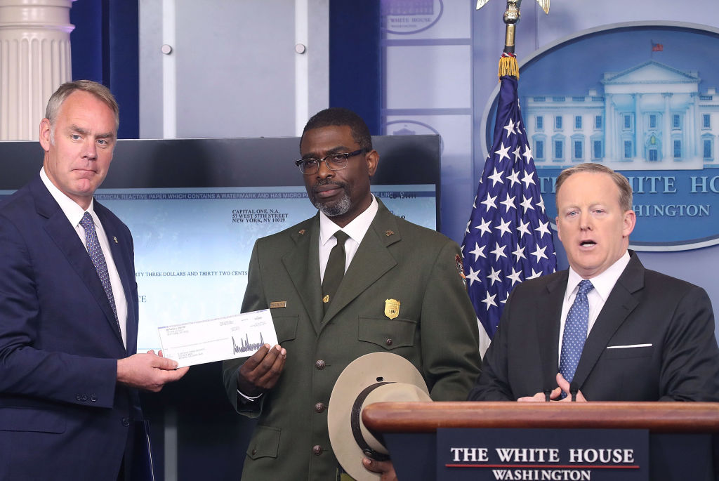 Former White House press secretary Sean Spicer and former Interior Secretary Ryan Zinke handing President Trump's first quarter salary check Tyrone Brandyburg, Harpers Ferry National Historical Park Superindendant, of the the National Park Service on April 3, 2017 (CREDIT: Mark Wilson/Getty Images)