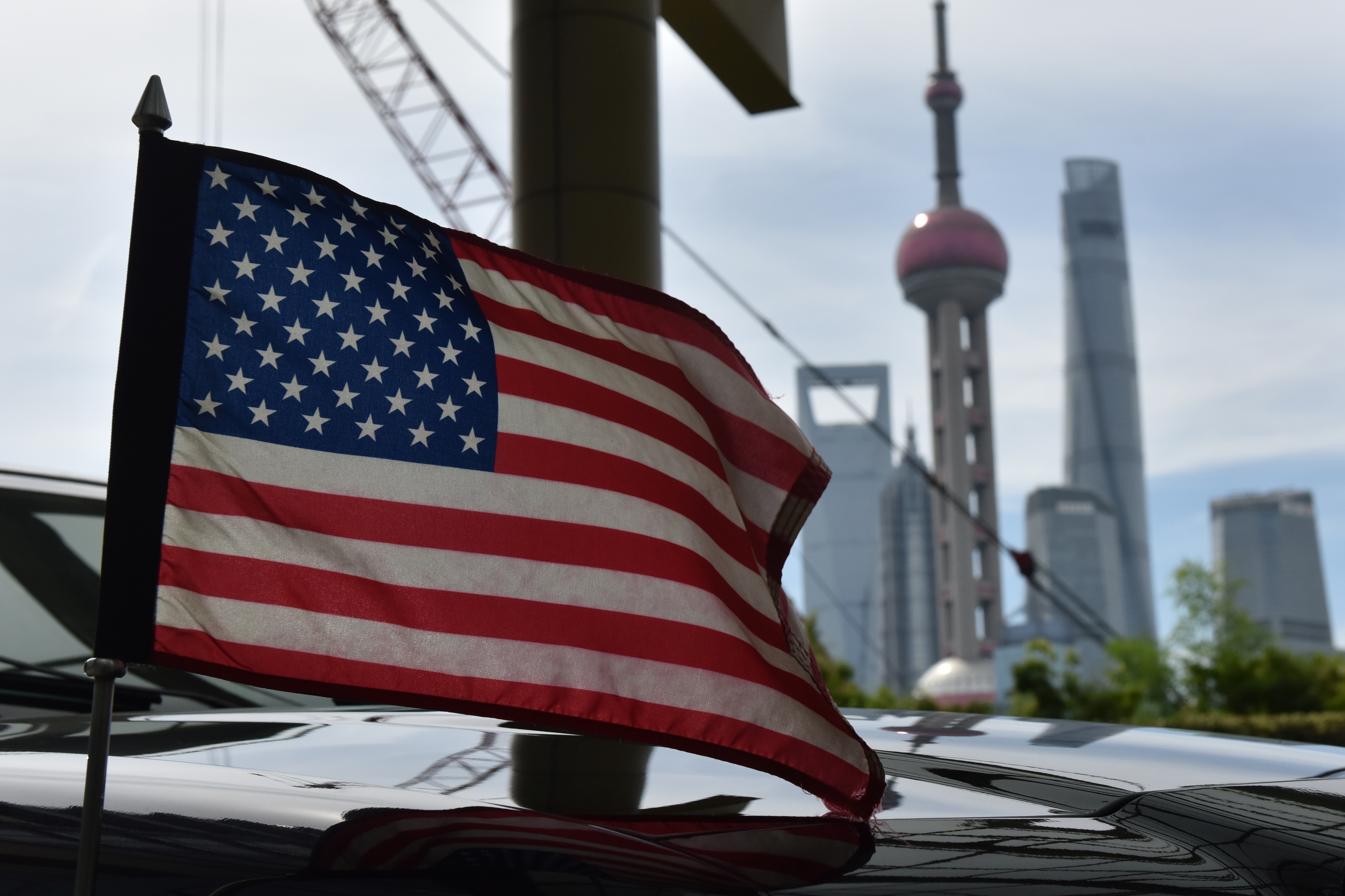A US flag flies on a US consulate car with the backdrop of buildings in the Lujiazui financial district, outside a hotel where US trade negotiators are staying in Shanghai on July 31, 2019. - US and Chinese negotiators held talks aimed at resolving their year-long trade war after President Donald Trump warns China that getting a deal would be tougher if it waits for next year's US election. CREDIT: GREG BAKER/AFP/Getty Images.