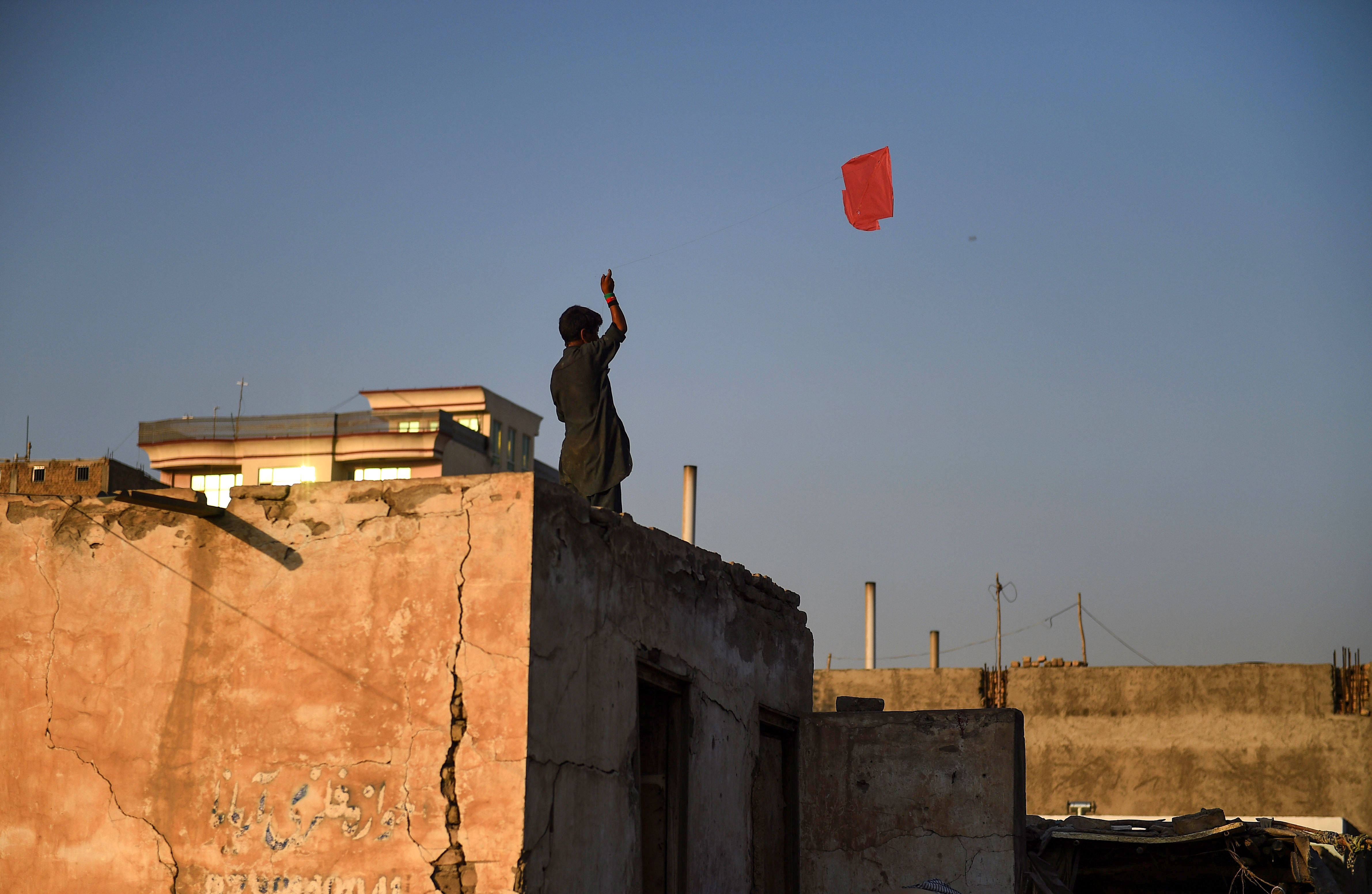 A boy flies a kite on the rooftop of a house in Mazar-i-Sharif. (FARSHAD USYAN/AFP/Getty Images)