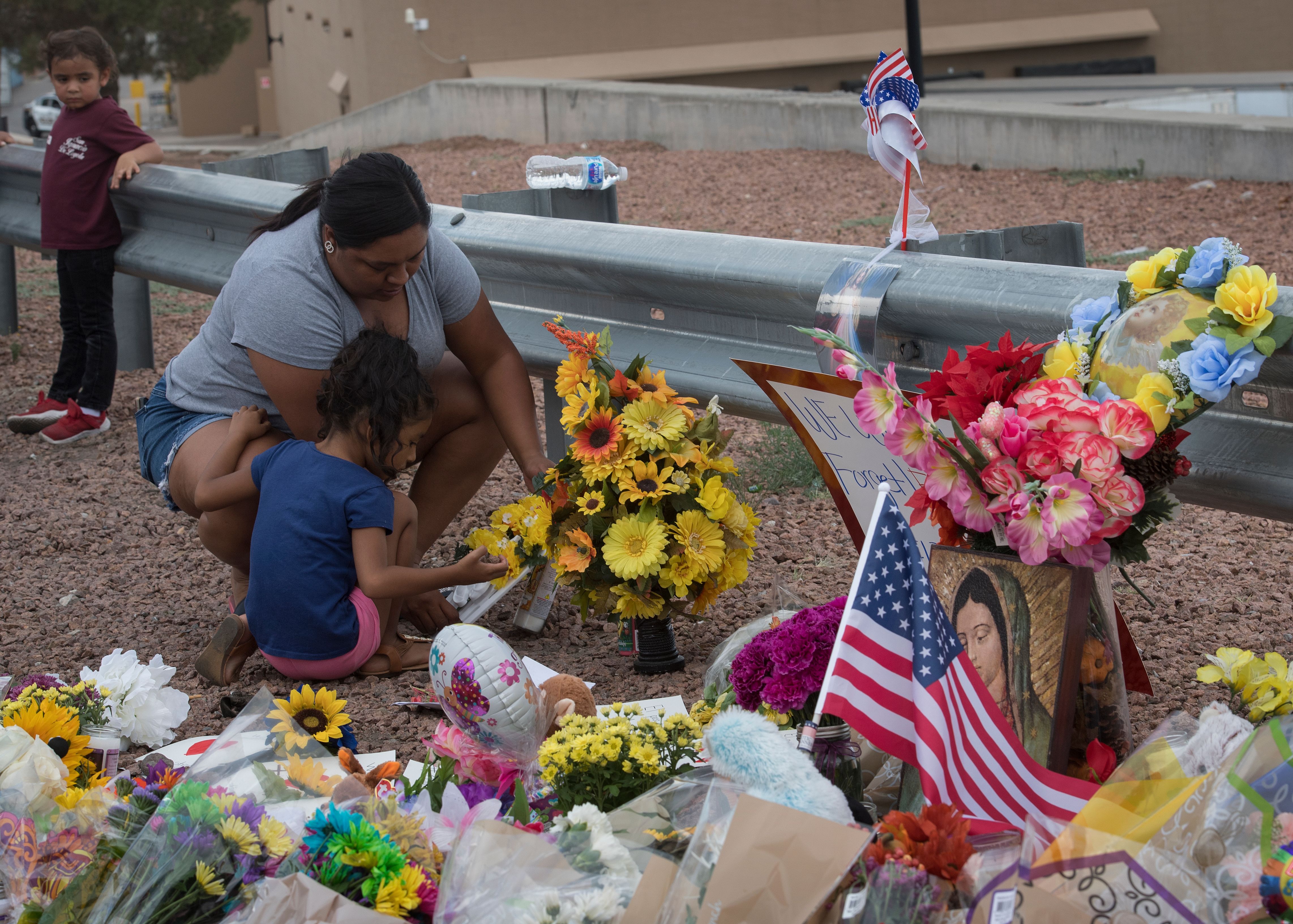 A family lights a candle at a makeshift memorial outside the Cielo Vista Mall Wal-Mart (background) where a shooting left 20 people dead in El Paso, Texas, on August 4, 2019. Credit: Mark RALSTON / AFP / Getty Images