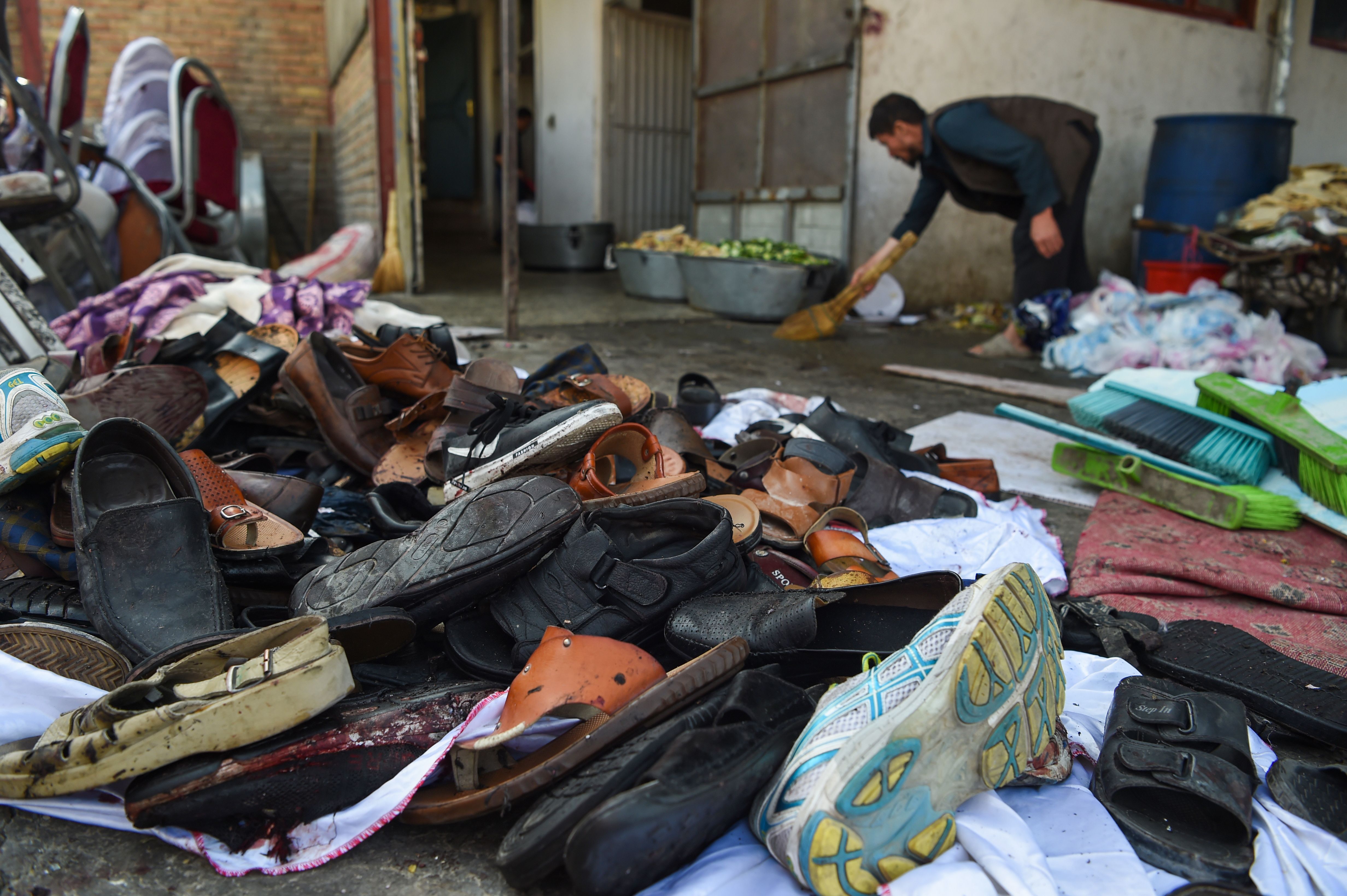 A man cleans an area next to a pile of shoes and sandals of victims outside a wedding hall after a deadly bomb blast in Kabul on August 18, 2019. - More than 60 people were killed and scores wounded in an explosion targeting a wedding in the Afghan capital, authorities said on August 18, the deadliest attack in Kabul in recent months. (Photo by Wakil KOHSAR / AFP) (Photo credit should read WAKIL KOHSAR/AFP/Getty Images)