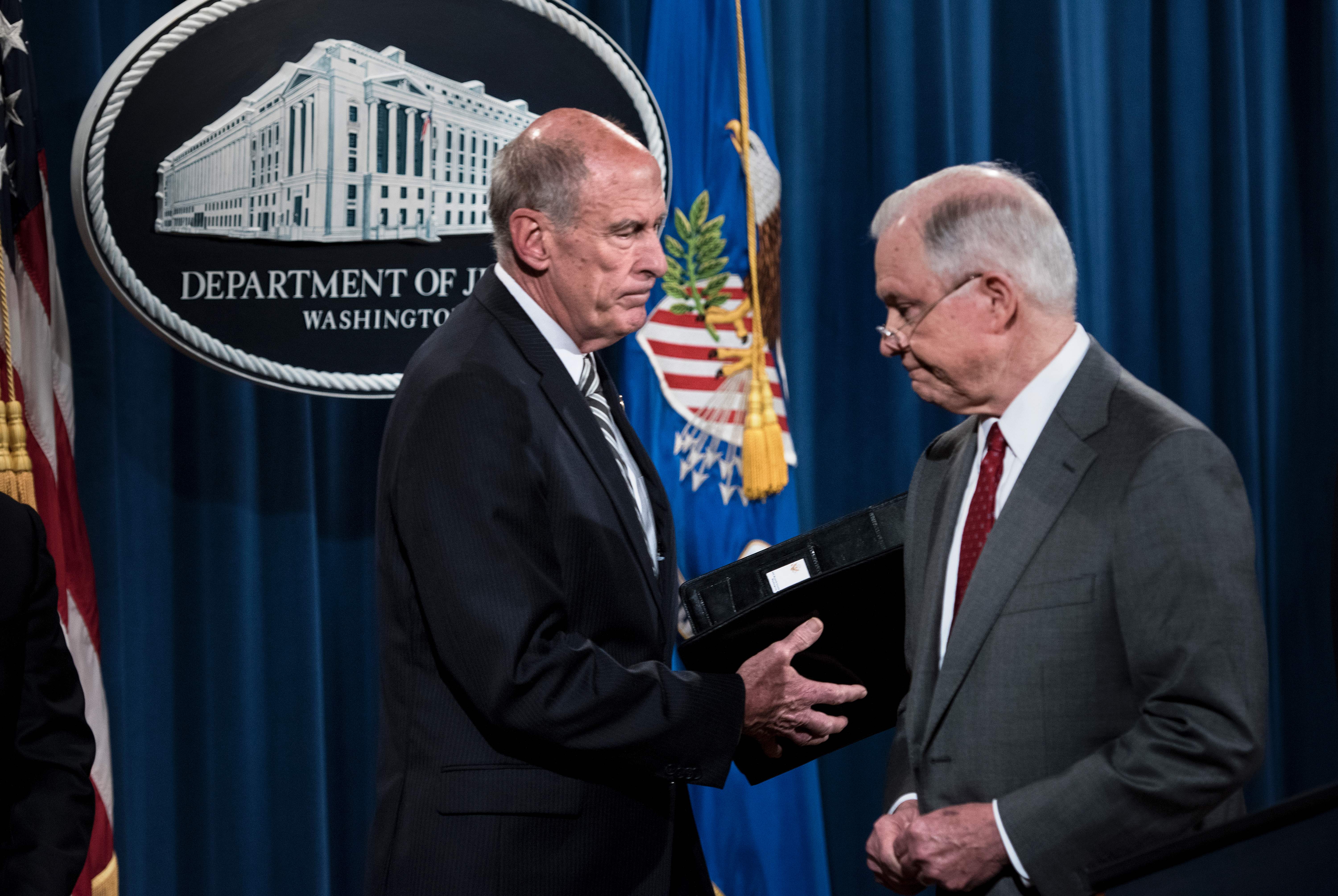 The outgoing Director of National Intelligence, Dan Coats, greets former Attorney General Jeff Sessions at a Justice Department press conference during on Aug. 4, 2017, in Washington, D.C. CREDIT: BRENDAN SMIALOWSKI/AFP/Getty Images